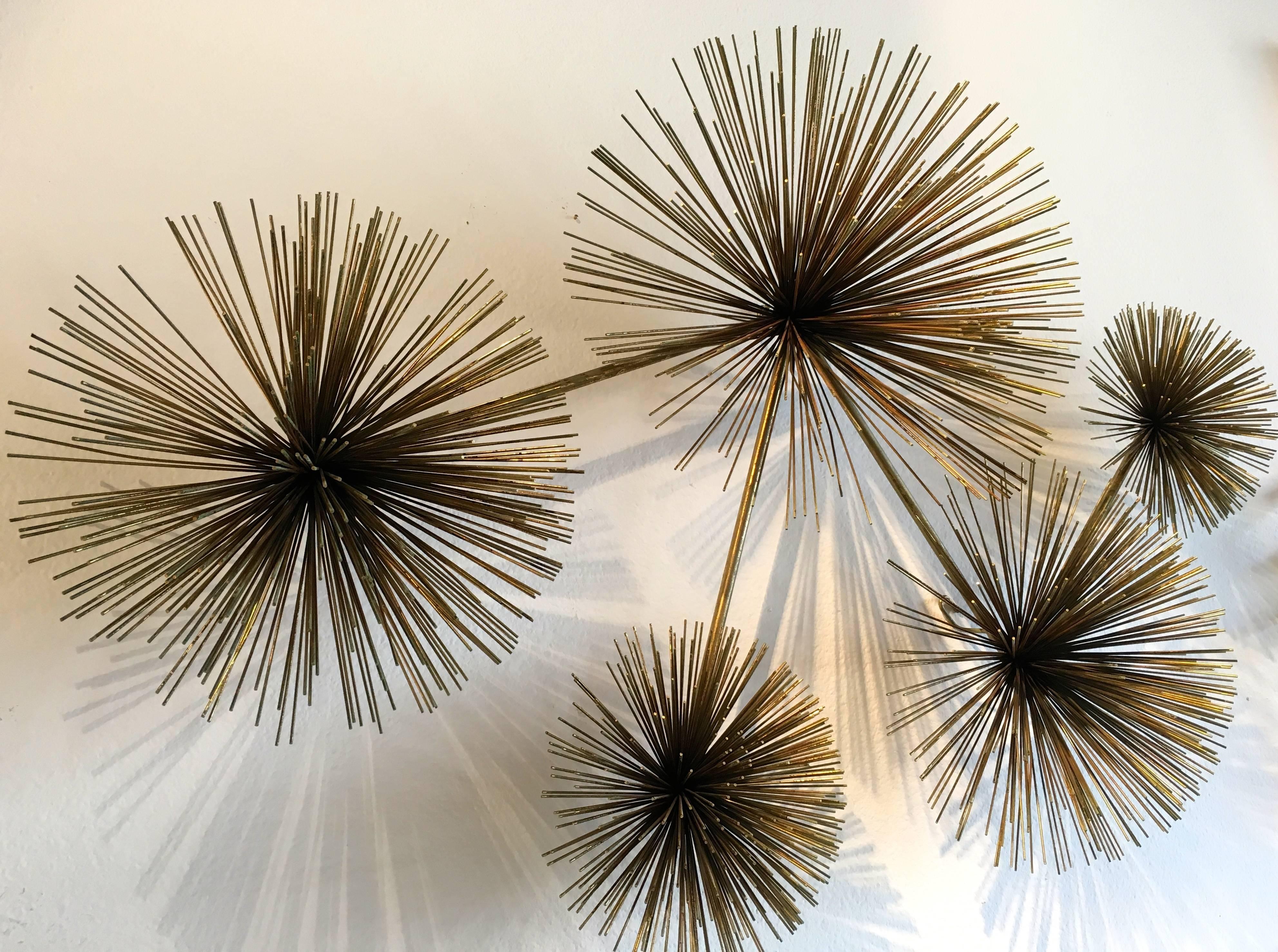 Iconic Curtis Jere wall sculpture featuring five brass sea urchins of varying sizes connected by slender brass rods. Sculpture is designed to hang by its one to three hooks depending on the display angle preferred.