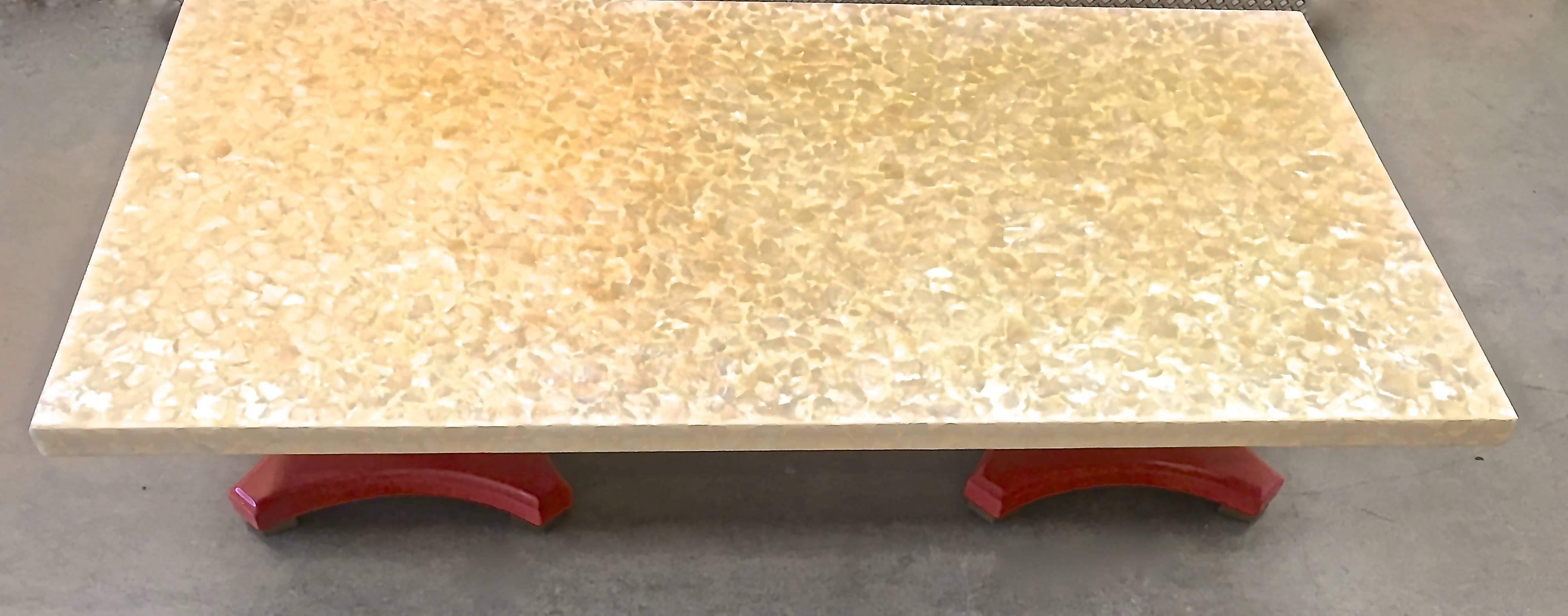 Substantial Mid-Century Modern cocktail table literally sparkles with its capiz shell top. The Hollywood Regency double base is lacquered in a brilliant persimmon color with gilded feet.