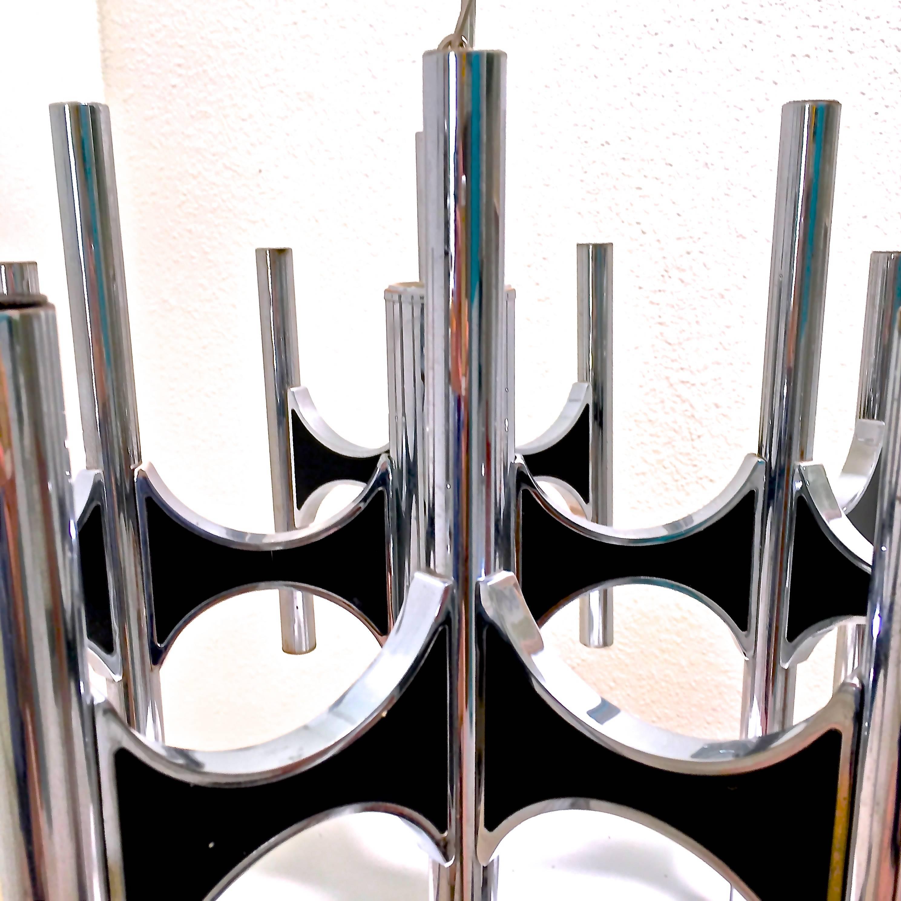 1960s-era Mid-Century Modern twelve-arm chandelier by Gaetano Sciolari is both sleek and dramatic. Chrome tubes are connected w/black enameled buttresses to accommodate 24 bulbs for upward and downward lighting.