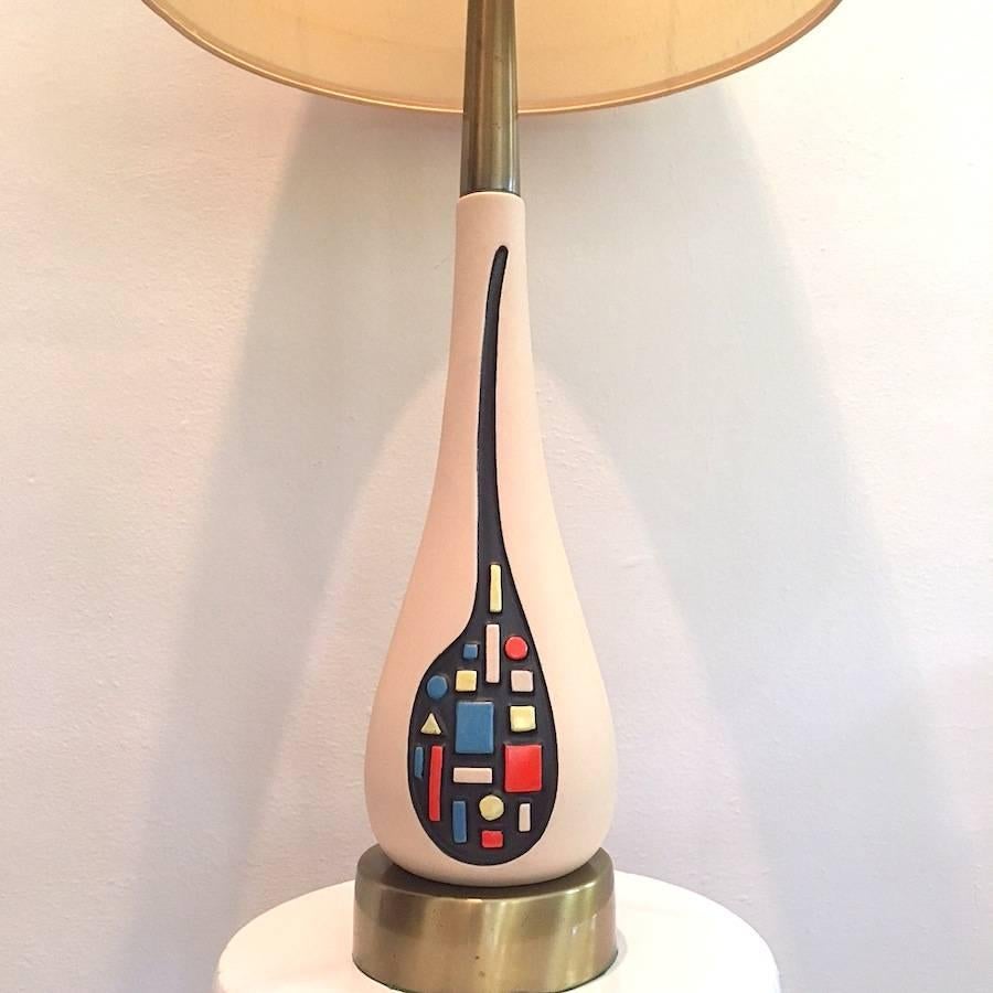 Eye-catching and elegant Mid-Century Modern Italian ceramic lamp with creme colored body featuring a colorful raised geometric modernist design in primary colors on a black ground. Tall and sleek yet substantial in weight.

  