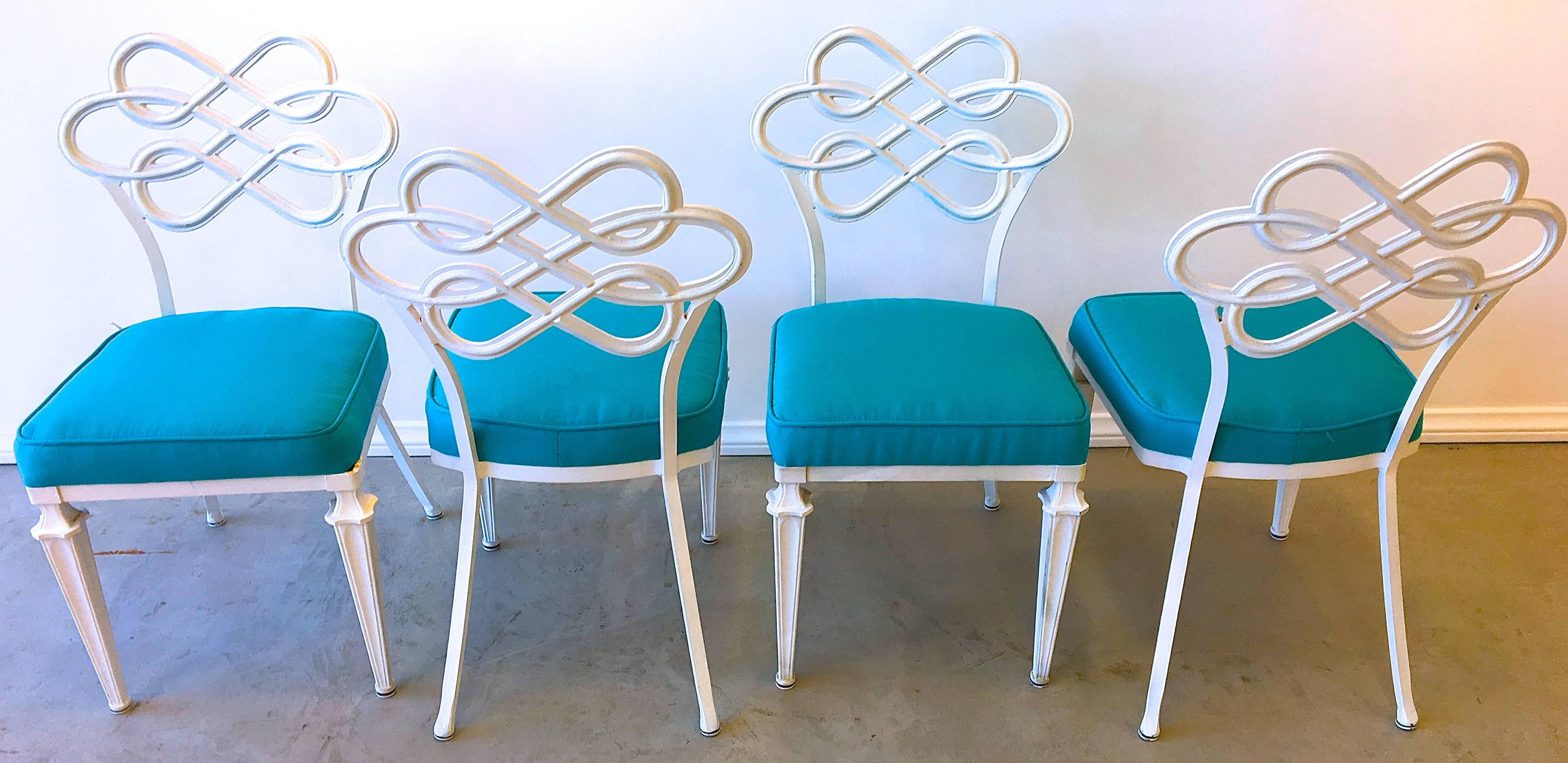 Mid-Century aluminium dining chairs epitomize the Hollywood Regency look with lyrical intertwining backs and neoclassic legs. The satin white finish juxtaposed with brilliant aqua sunbrella canvas lends a fresh look for dining indoors or on a