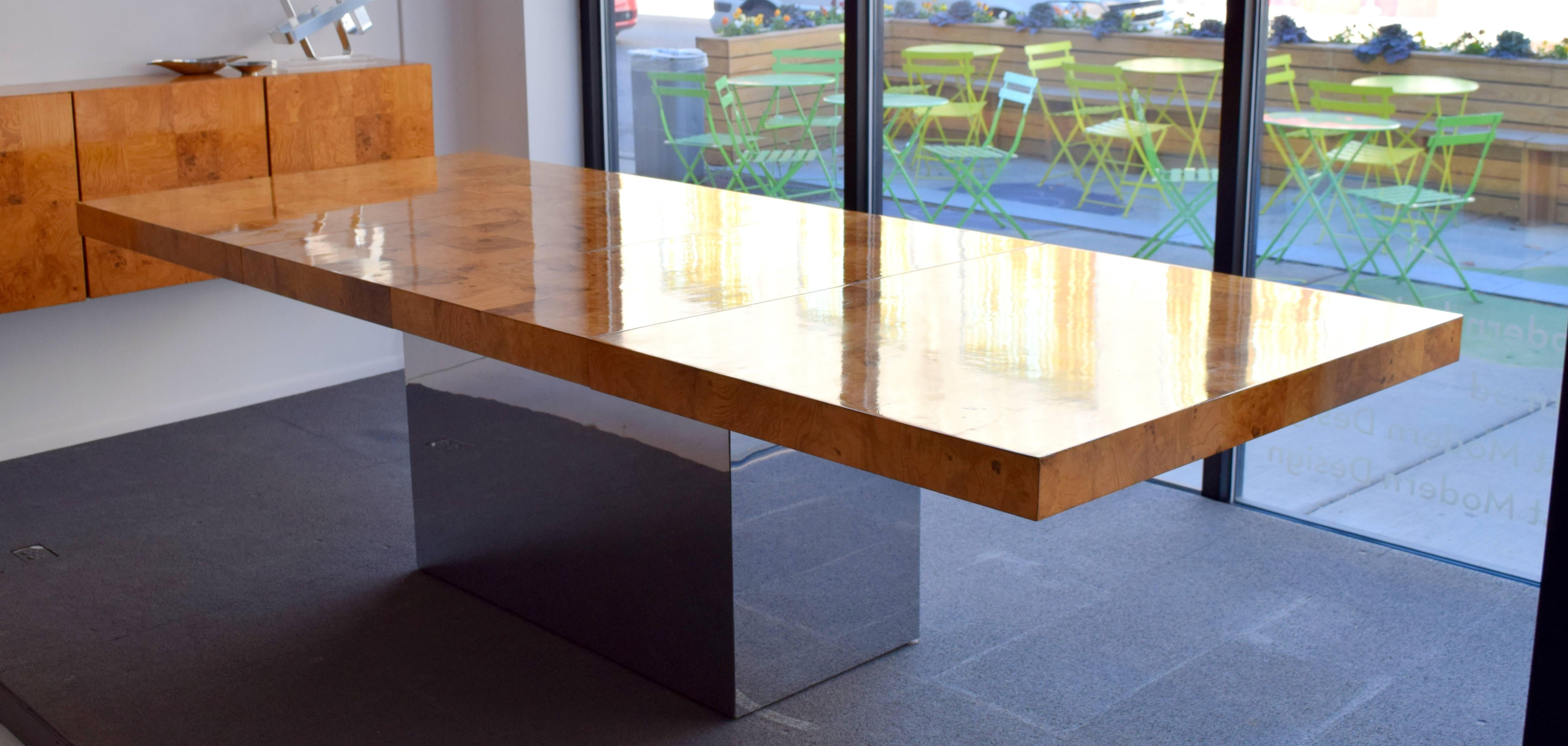 Impressive expandable dining table by Milo Baughman in patchwork burl wood with polished stainless steel base. With both leaves table expands to 110