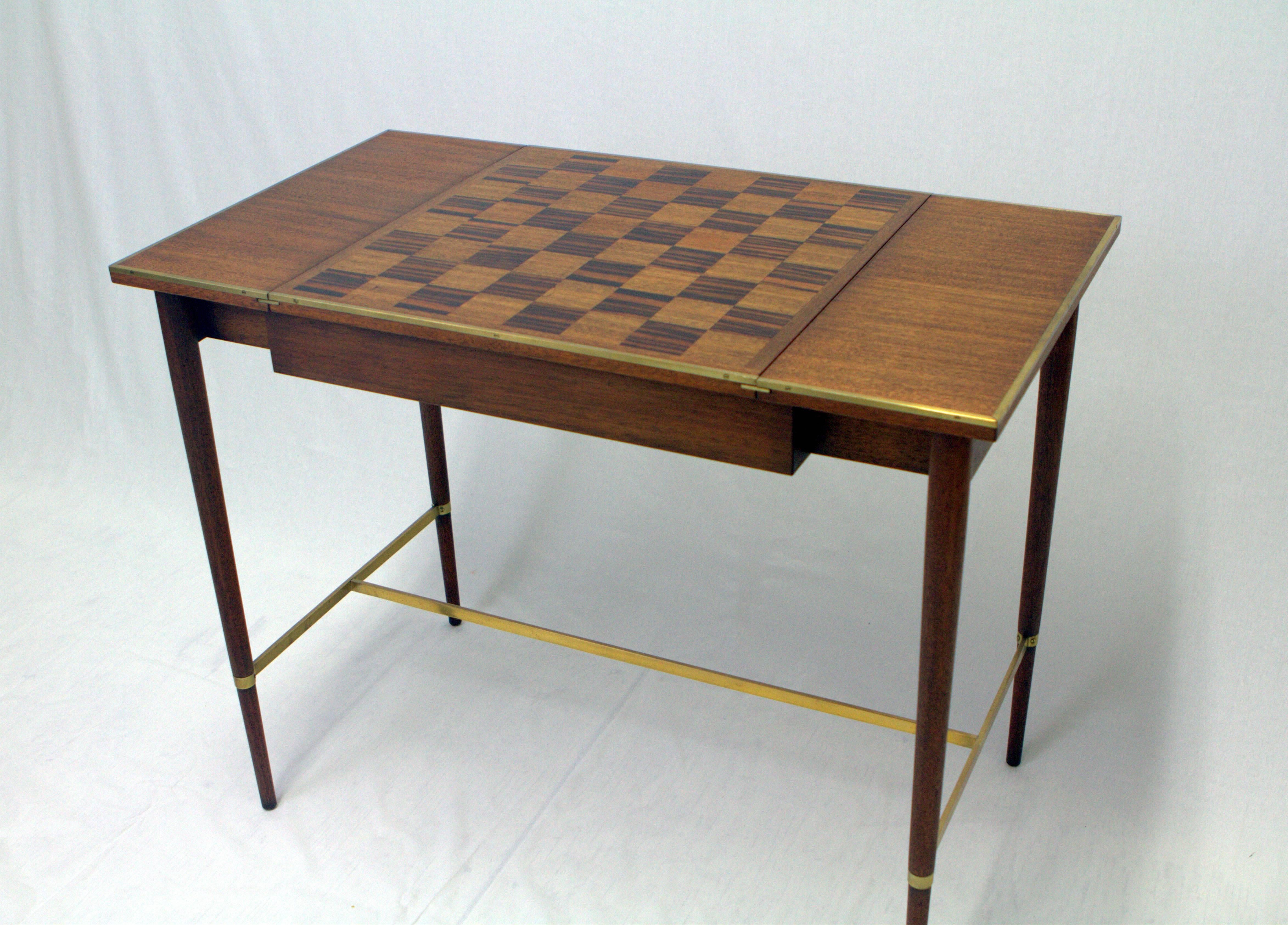 Paul McCobb game table for H. Sacks and Sons, circa 1950s. Elegant scale and function executed in mahogany, walnut, Macassar ebony and brass. Checkerboard top slides to reveal lined storage compartment and original tag.
Wonderful original condition