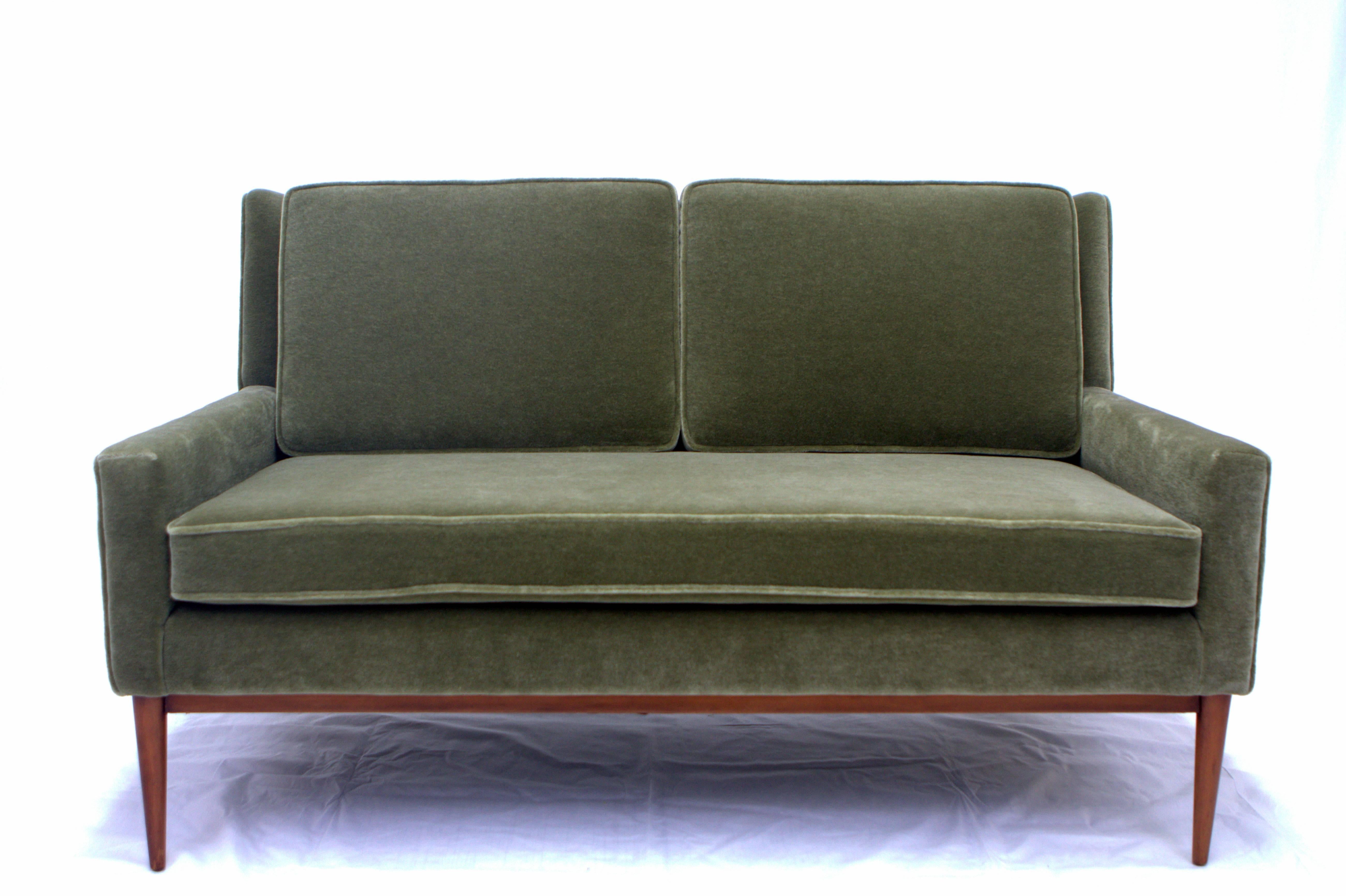 Paul McCobb loveseat for Directional reupholstered in olive/moss green mohair. Two back cushions resting on single seat cushion gives piece an elegant and refined proportion. Walnut frame refinished in medium walnut tone. Thick, plush mohair in a