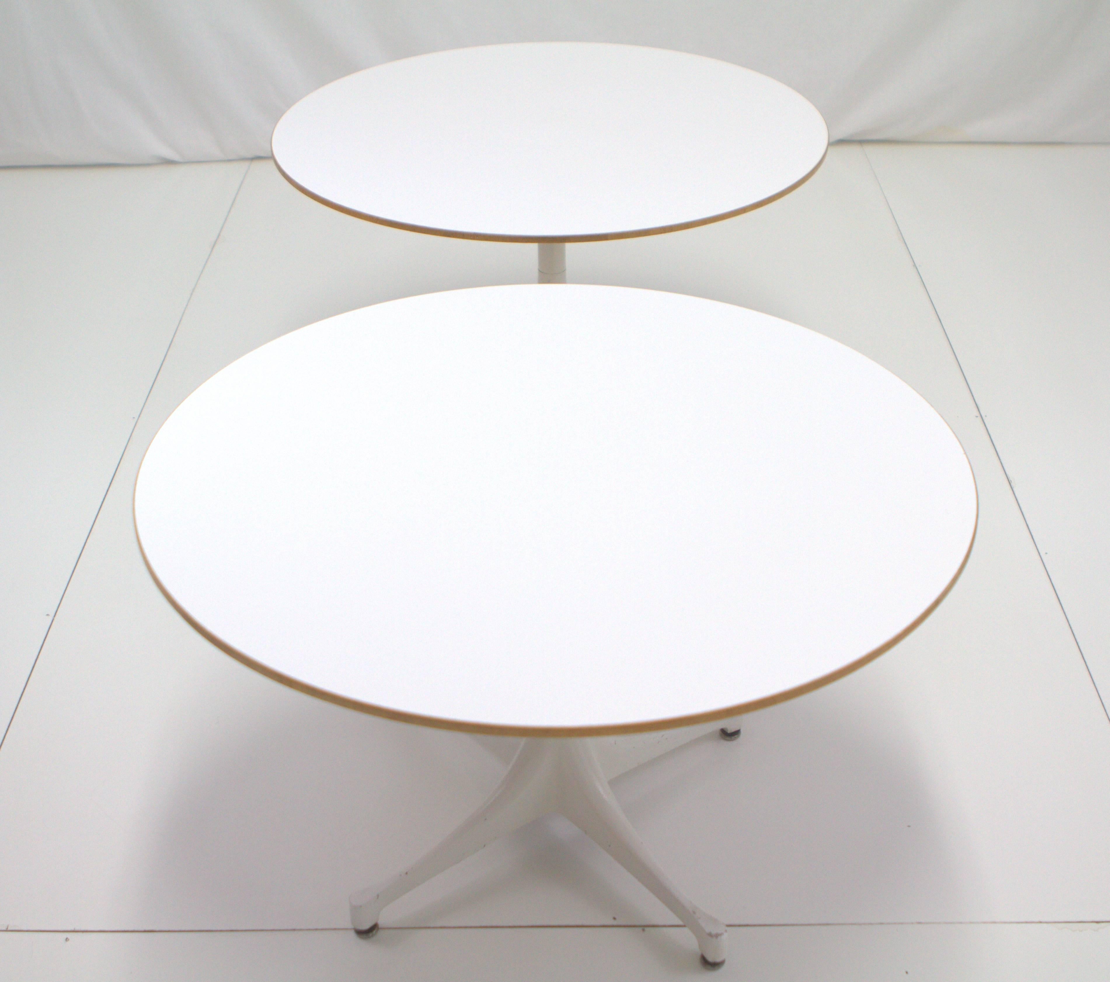 Pair of swag leg round end tables by George Nelson for Herman Miller. White micarta tops banded by wood with swag leg white painted aluminum base. Original vintage condition with wear to base and tops. One table has some veneer missing from wood