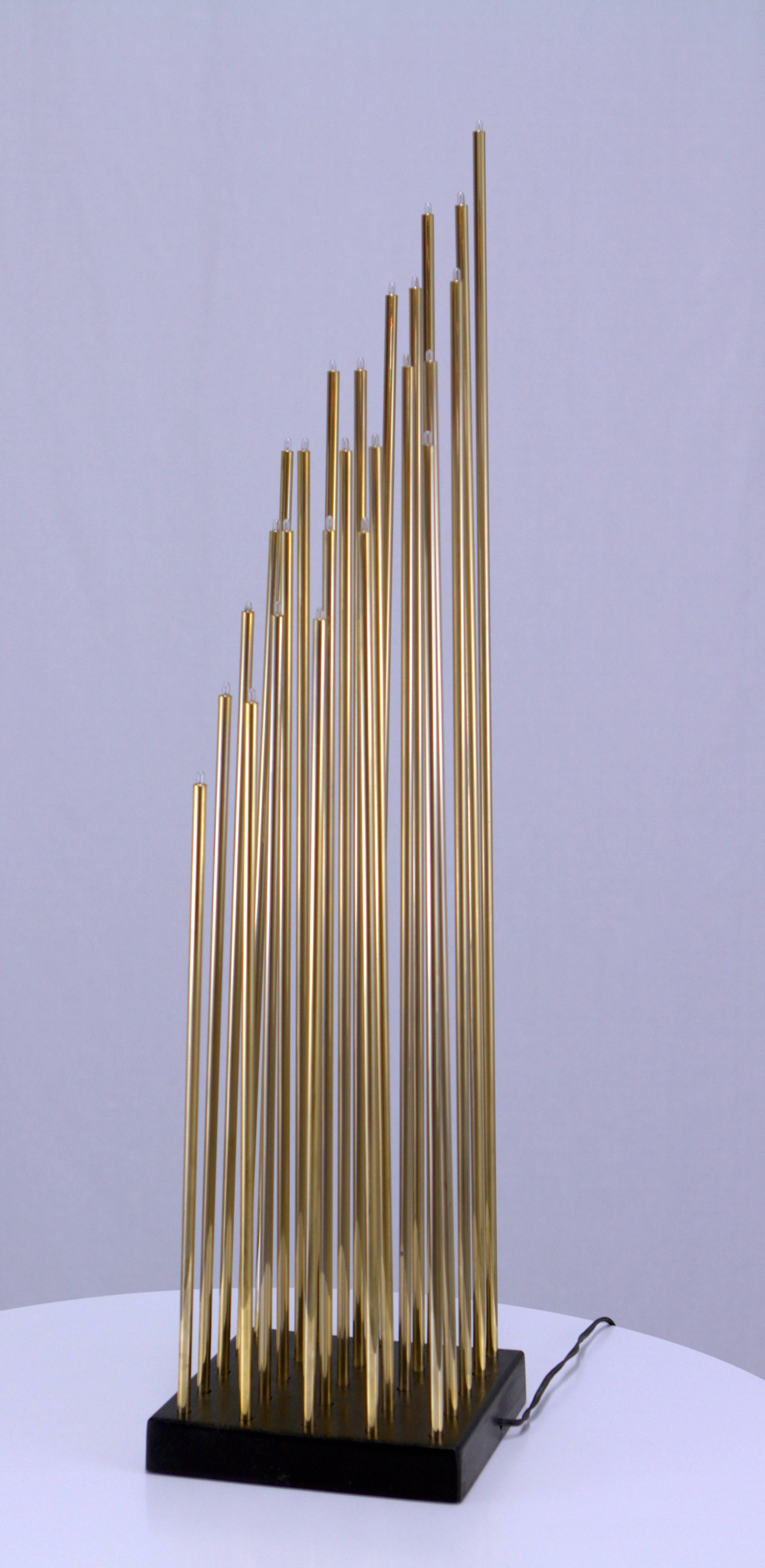 Amazing light sculpture consisting of 25 slender brass tubes with miniature bulbs emanating from a square ebonized wood base. Measures: 5/16