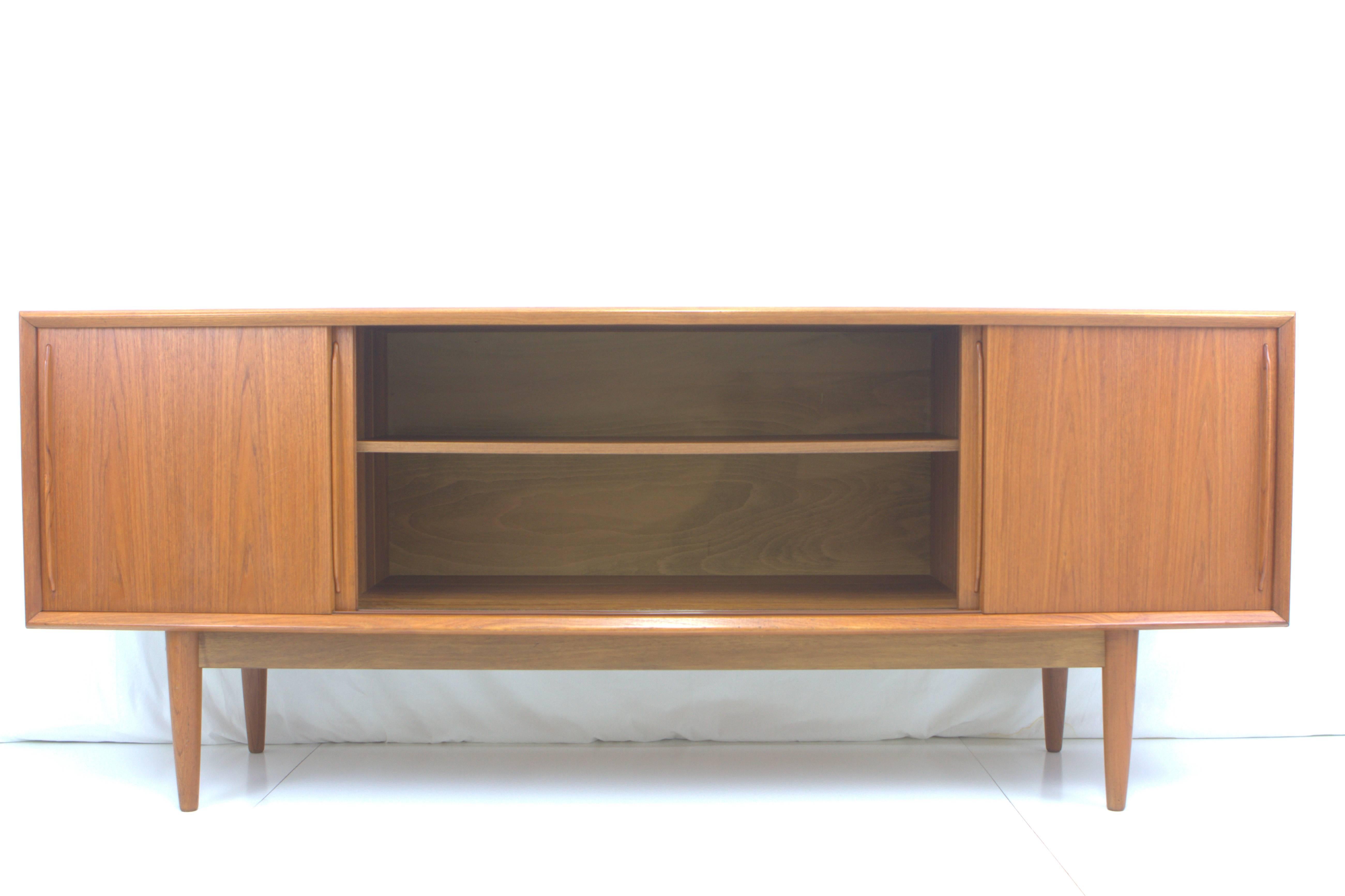 Danish teak perfection. Graceful bowfront credenza by Arne Vodder for H.P. Hansen, Denmark, circa 1960s. Open storage with adjustable shelves behind sliding doors in middle and right side with four shallow drawers on left, one drawer divided for