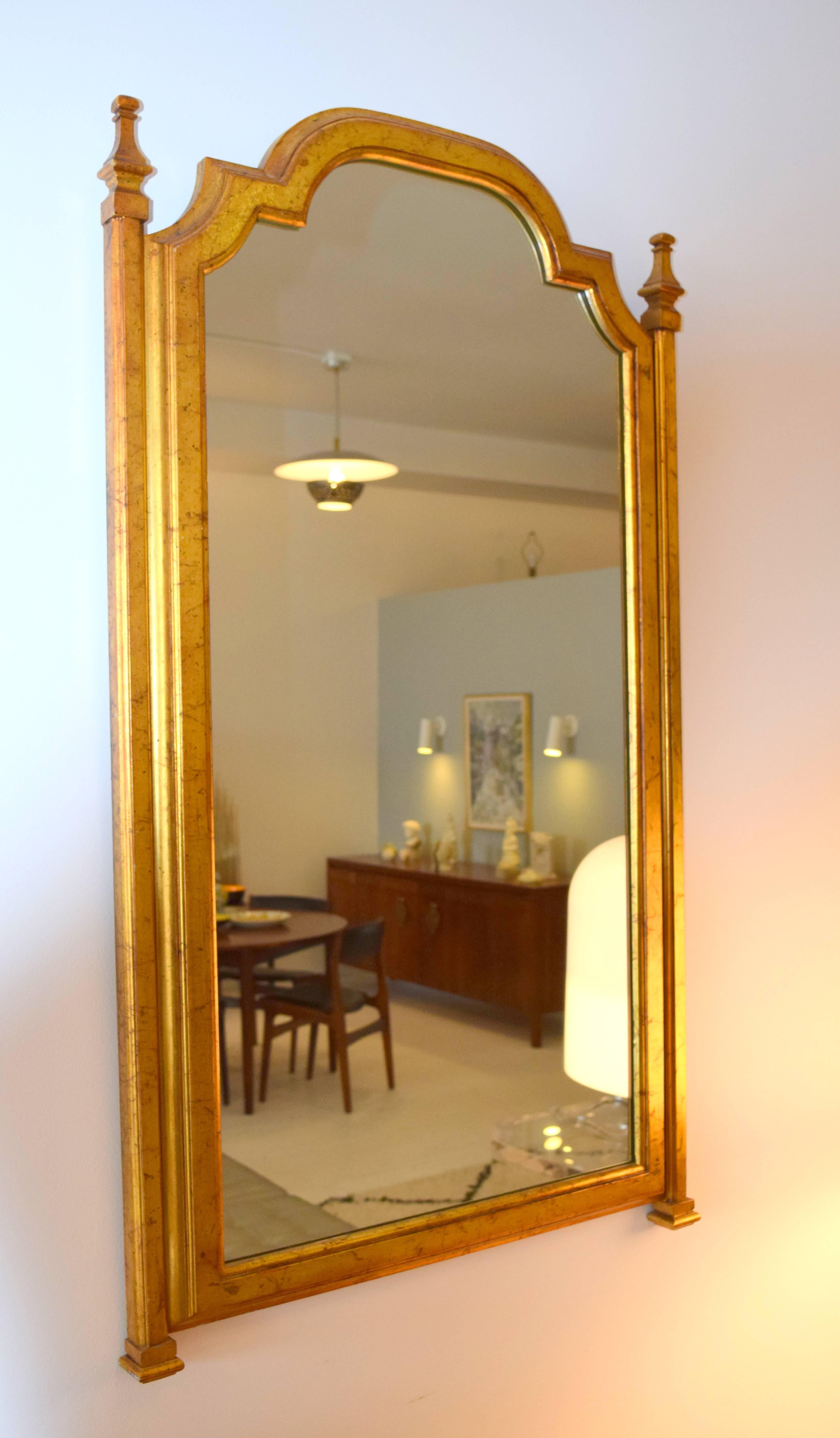 Regal gold leafed wood frame mirror with expressive form. Dramatic scale and gilt technique exudes quality and elegance.
