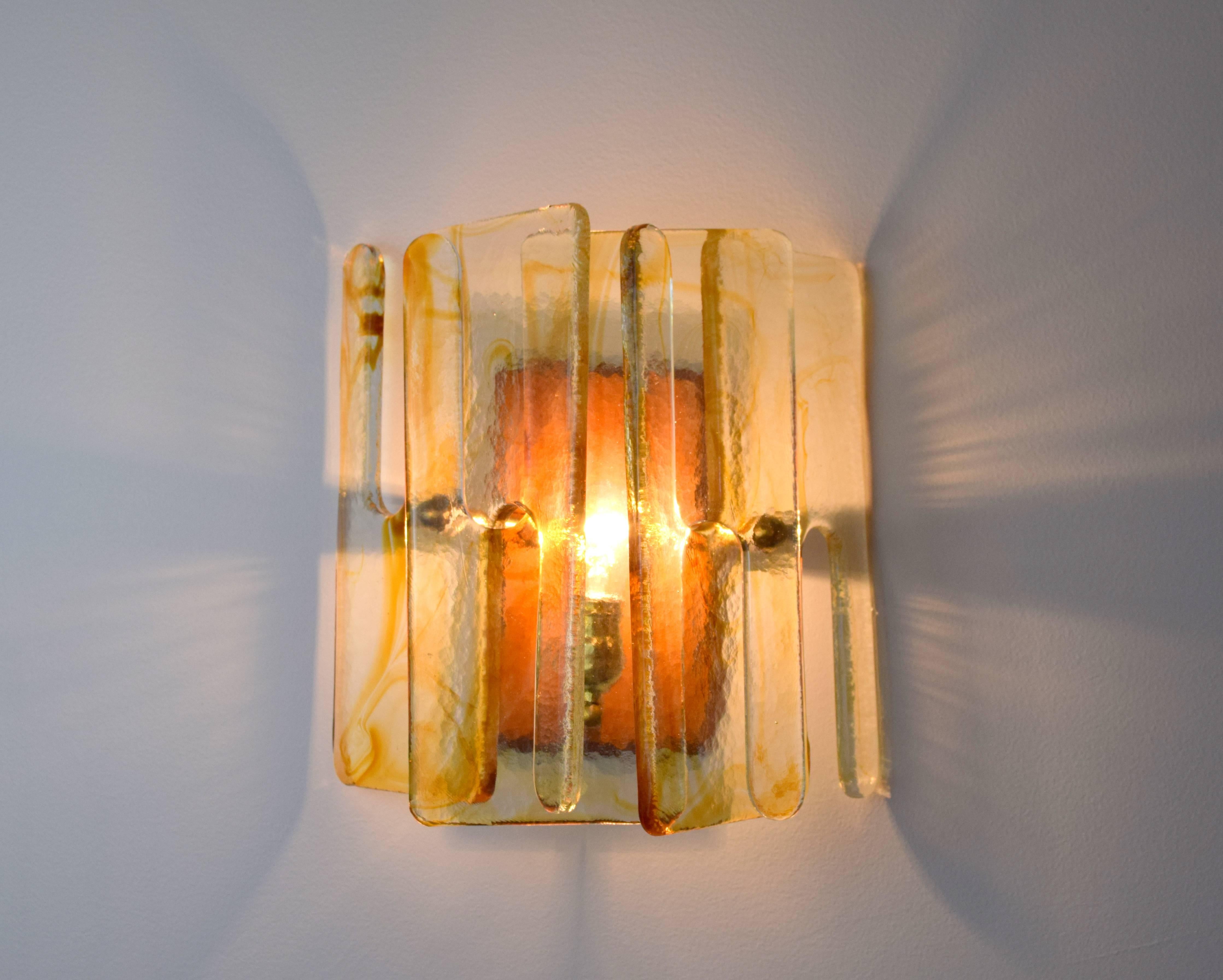 Beautiful clear and amber Murano glass sconces by Mazzega. Constructed of three interlocking glass panels with brass fittings mounted on wood backplate with single brass light socket. Each glass panel in an N shape being 7.75