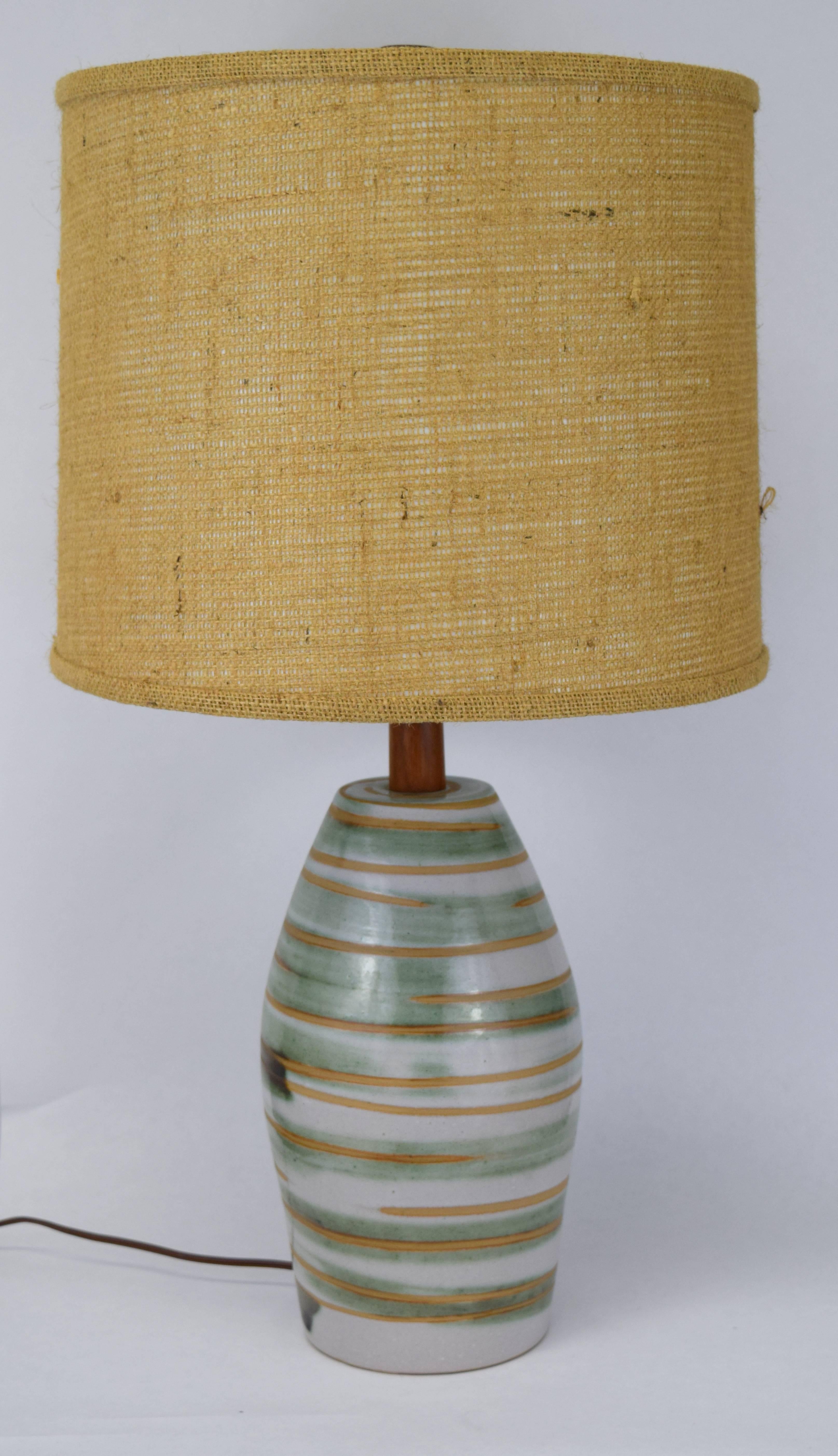 Medium size Marshall Studios swirled glaze table lamp with teak accents. Lovely green, cream, tan swirls to base with incised signature and original UL sticker to socket. Measures: 15.5
