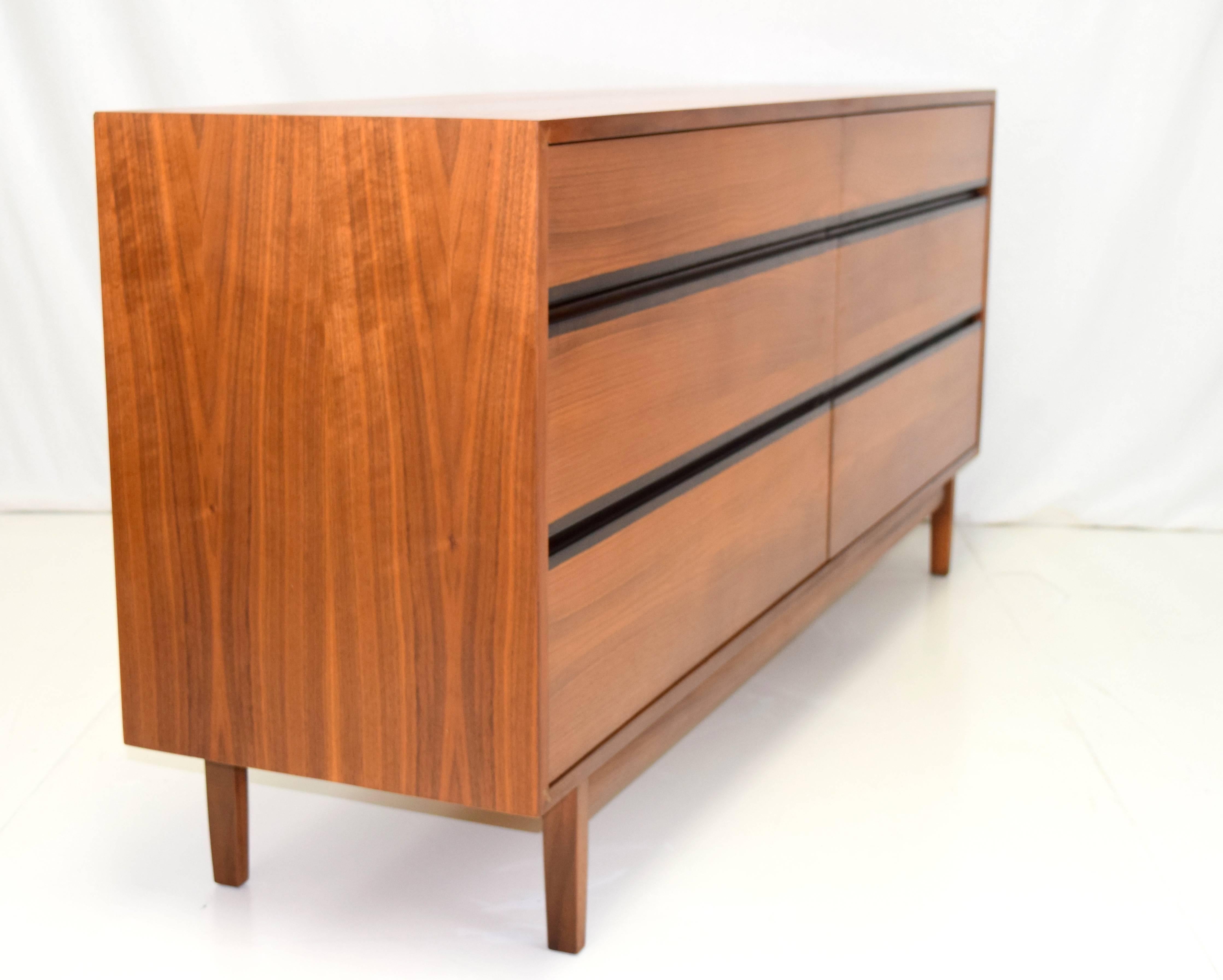 Perfectly scaled walnut six-drawer dresser by Kipp Stewart for Calvin Furniture. Bookmatched drawer fronts creates a fluidity with contrasting bands of full length recessed drawer pulls. Front corners are mitered with perpendicular tenons. Lovely