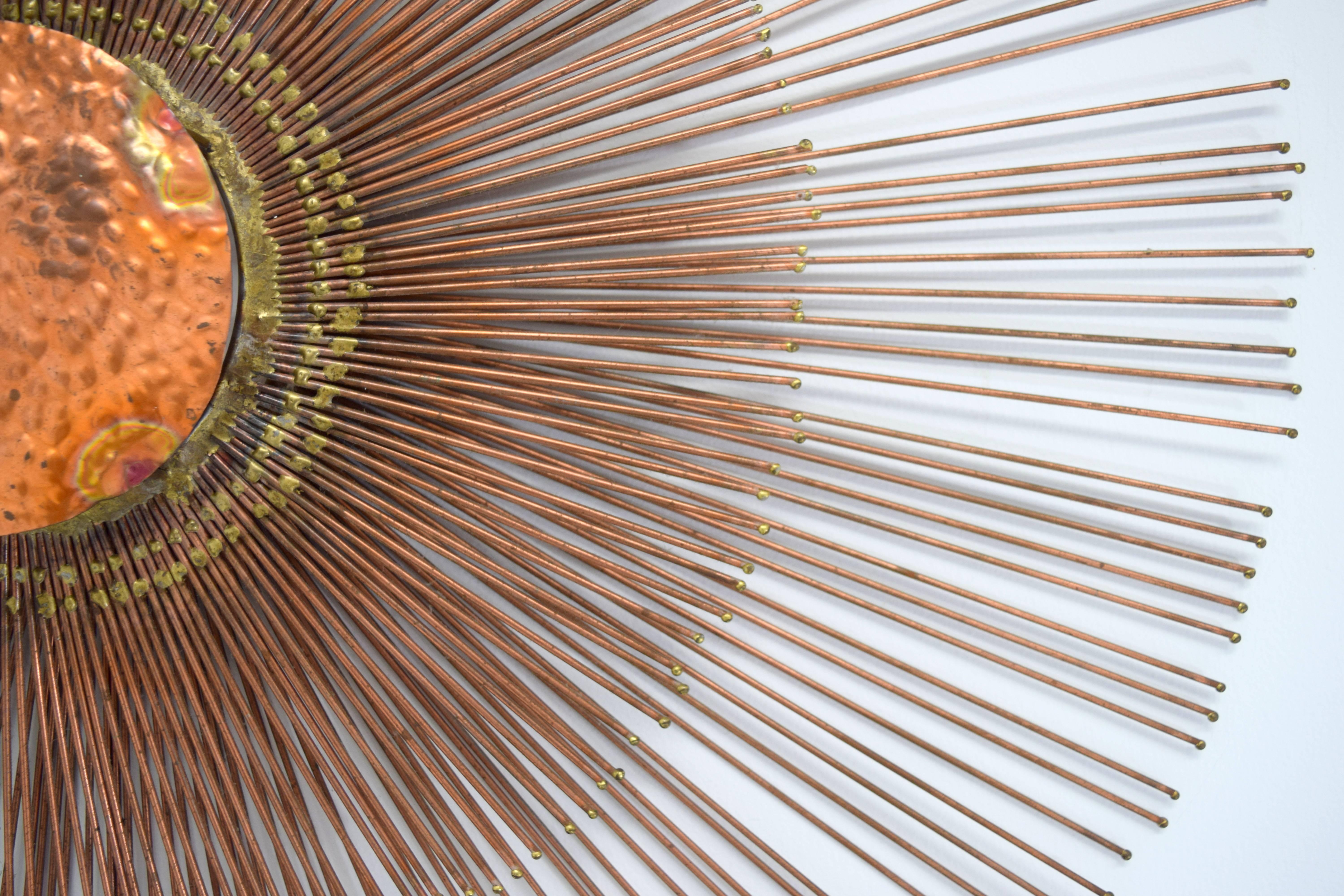 Striking copper wall sunburst wall sculpture by Curtis Jere. Two tiers of copper rods radiate around a central copper textured disc creating multi-level structured composition. Measure: Outer ring rays 29.25
