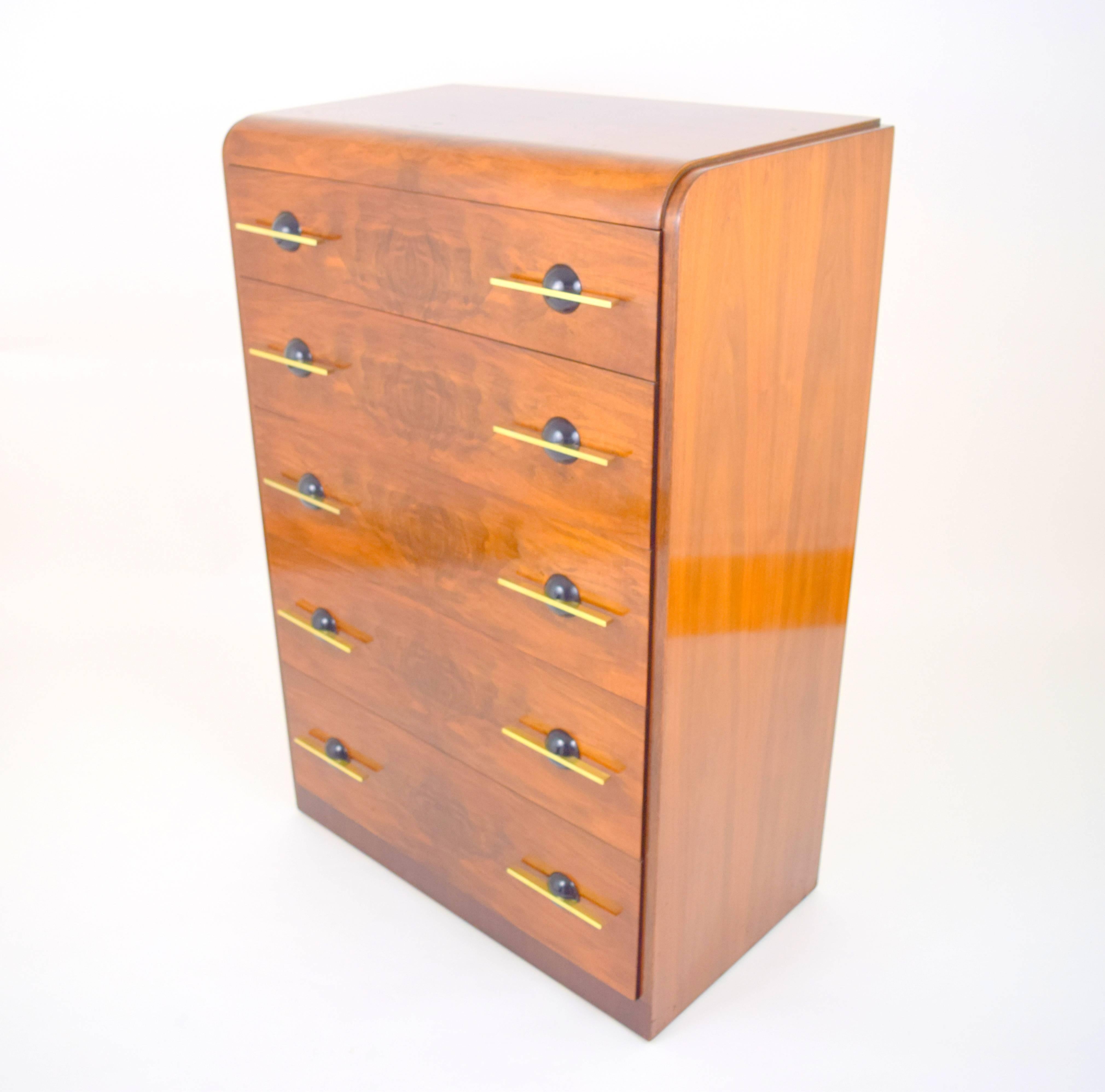 Stunning streamlined moderne chest of drawers by Donald Deskey. Walnut case with five waterfall burl wood front drawers with solid brass bar pulls through hemispherical ebonized wood back plates. Elegant and functional early American modernism in