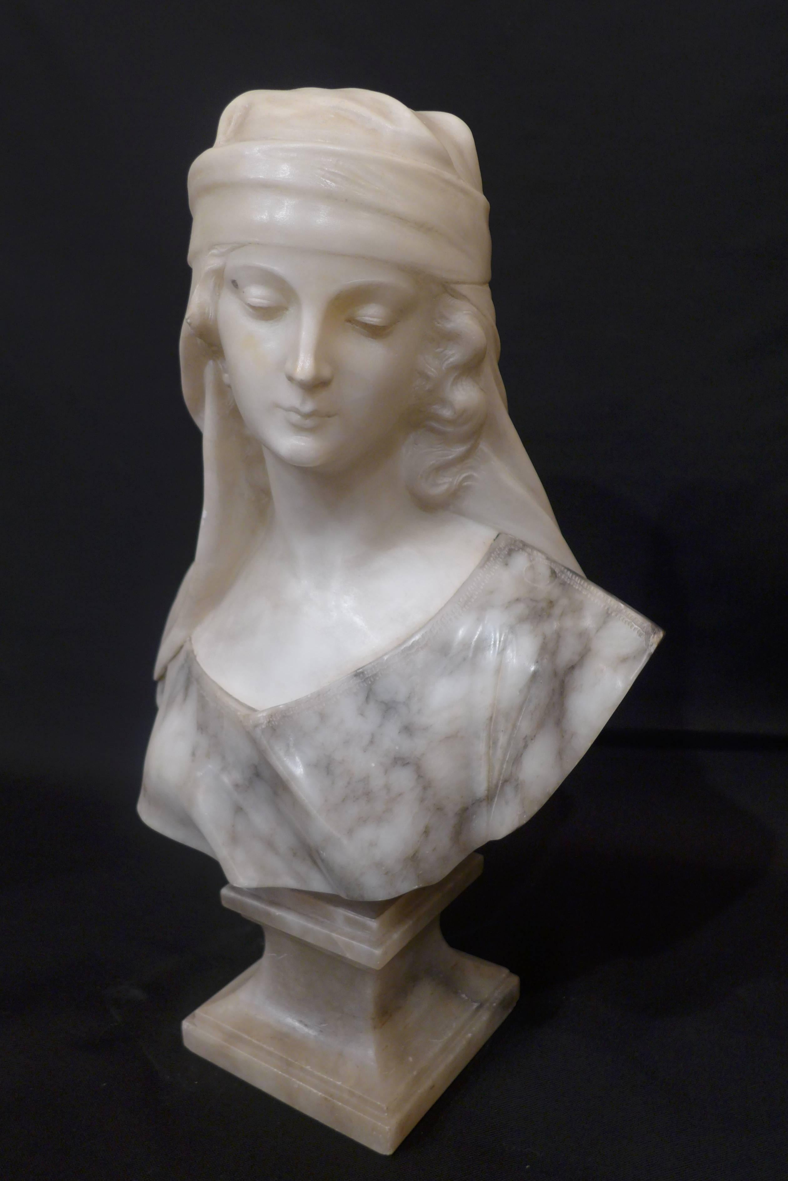 This sculpture represents an oriental woman bust, carved in alabaster, on a grey veined marble. 
It is signed on the back by the artist Guglielmo Pugi (1850-1915), born in Fiesole, a small town close to Florence.

Guglielmo Pugi carved the bust