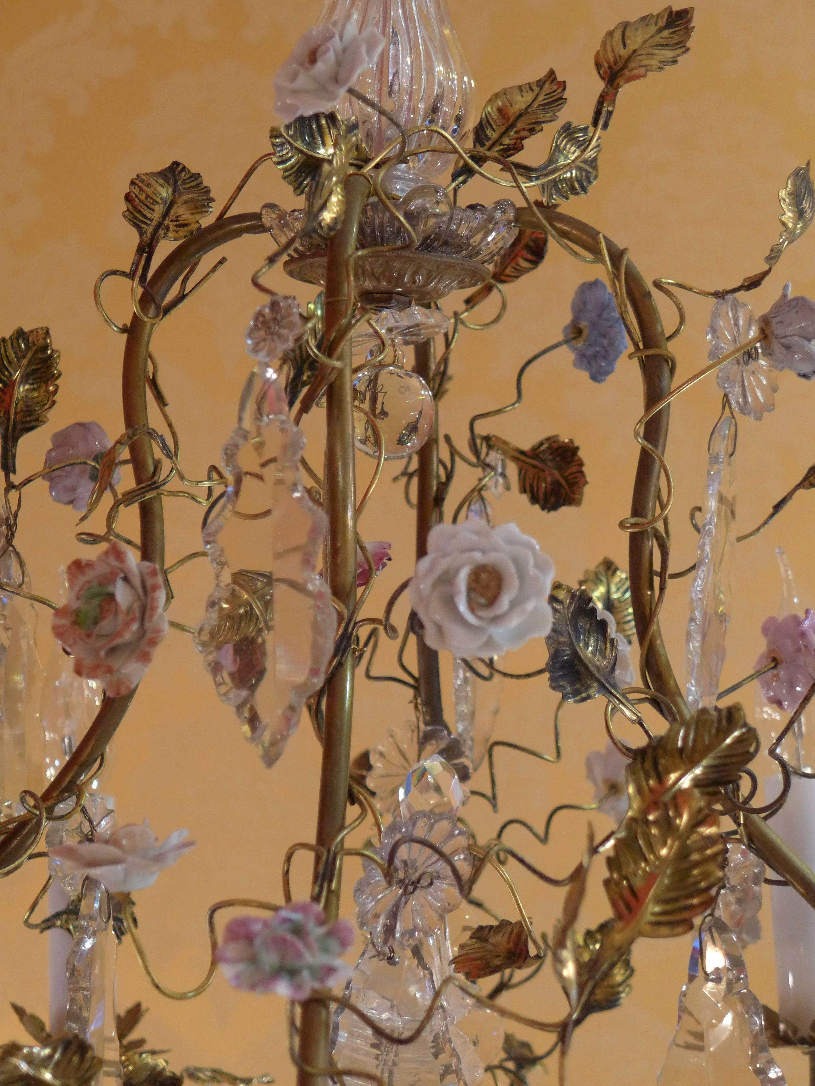 French Louis XV style, cage-form gilt bronze chandelier, with porcelain flowers and crystal, electrified with four lights. This chandelier features tree branches and foliage ended with polychromatic porcelain flowers. Cut crystal decoration of