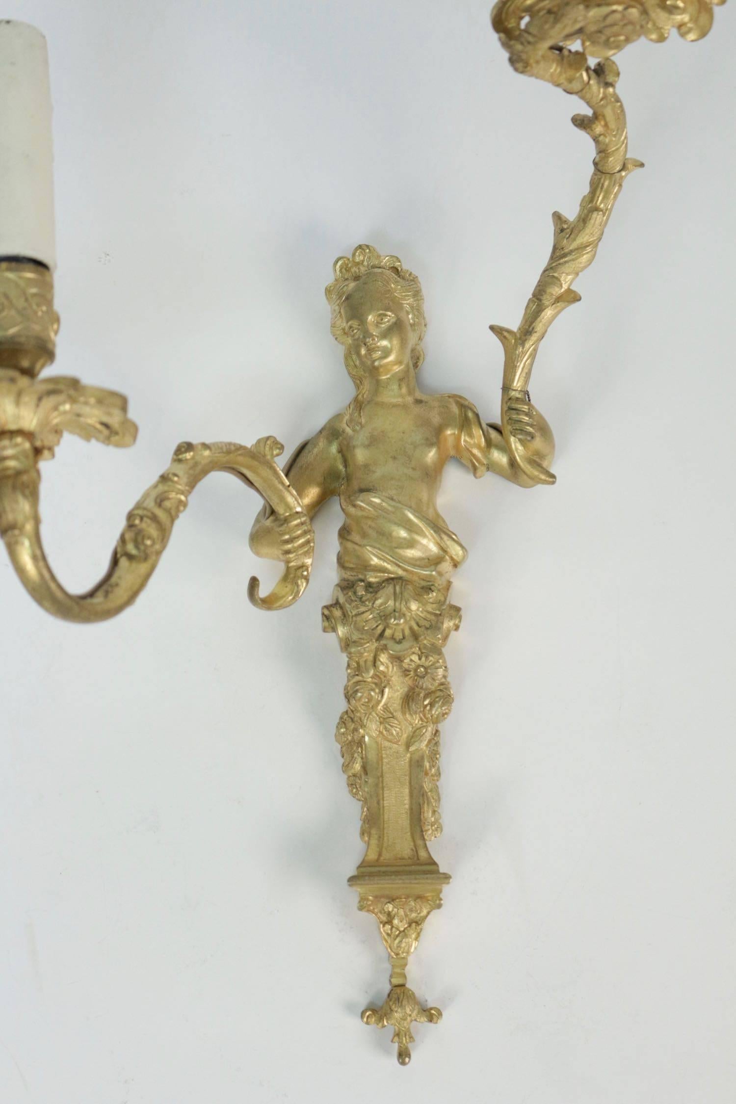 Interesting and lovely pair of French Regence style, two lights, ormolu sconces, finely chiseled, man and woman bust in a console with garland of flowers. Very beautiful original gilding. French work circa 1860-1870 French Regence style, 1715-1723 :