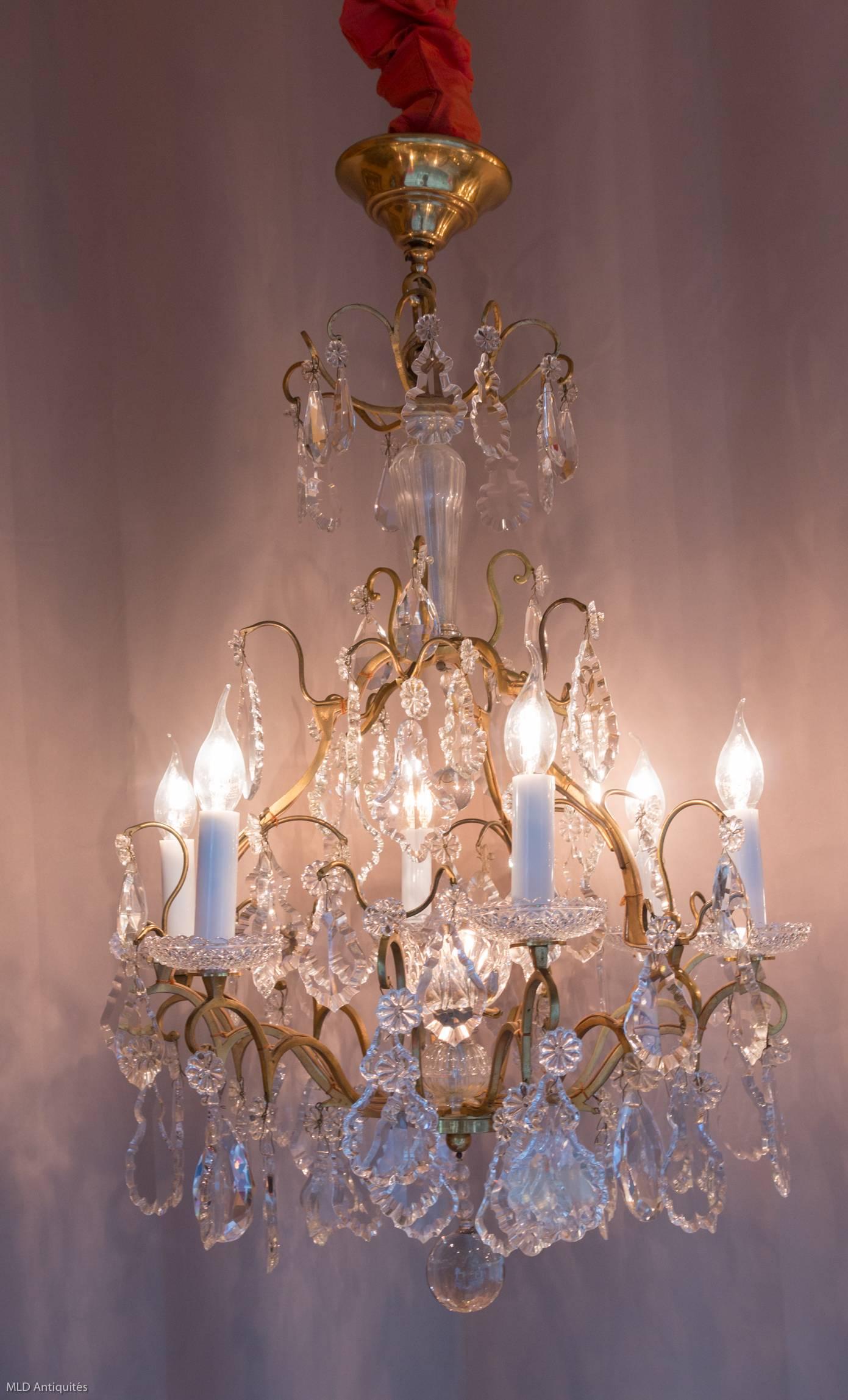 In original gilt bronze and hand-cut crystal, lovely small form cage chandelier in the classical Louis XV style. The chandelier is composed of six perimeter arm lights and one internal crystal flower light. Very fine quality white hand-cut crystal