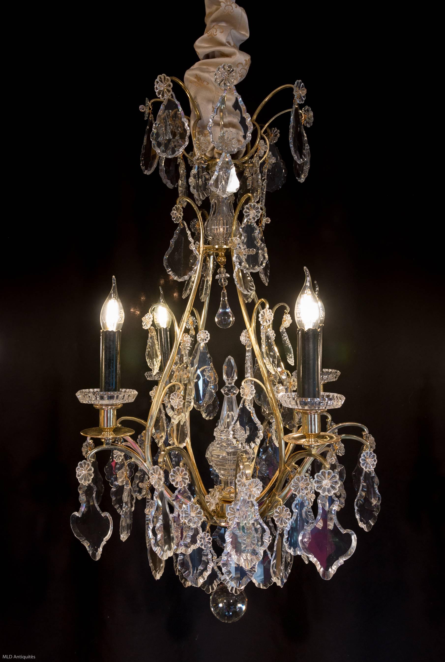 We have the pleasure to present you a lovely, original gilt bronze and hand cut crystal, small form cage chandelier in the Classic Louis XV style.
Our chandelier is composed of four perimeter arm lights, on the centre beautiful crystal