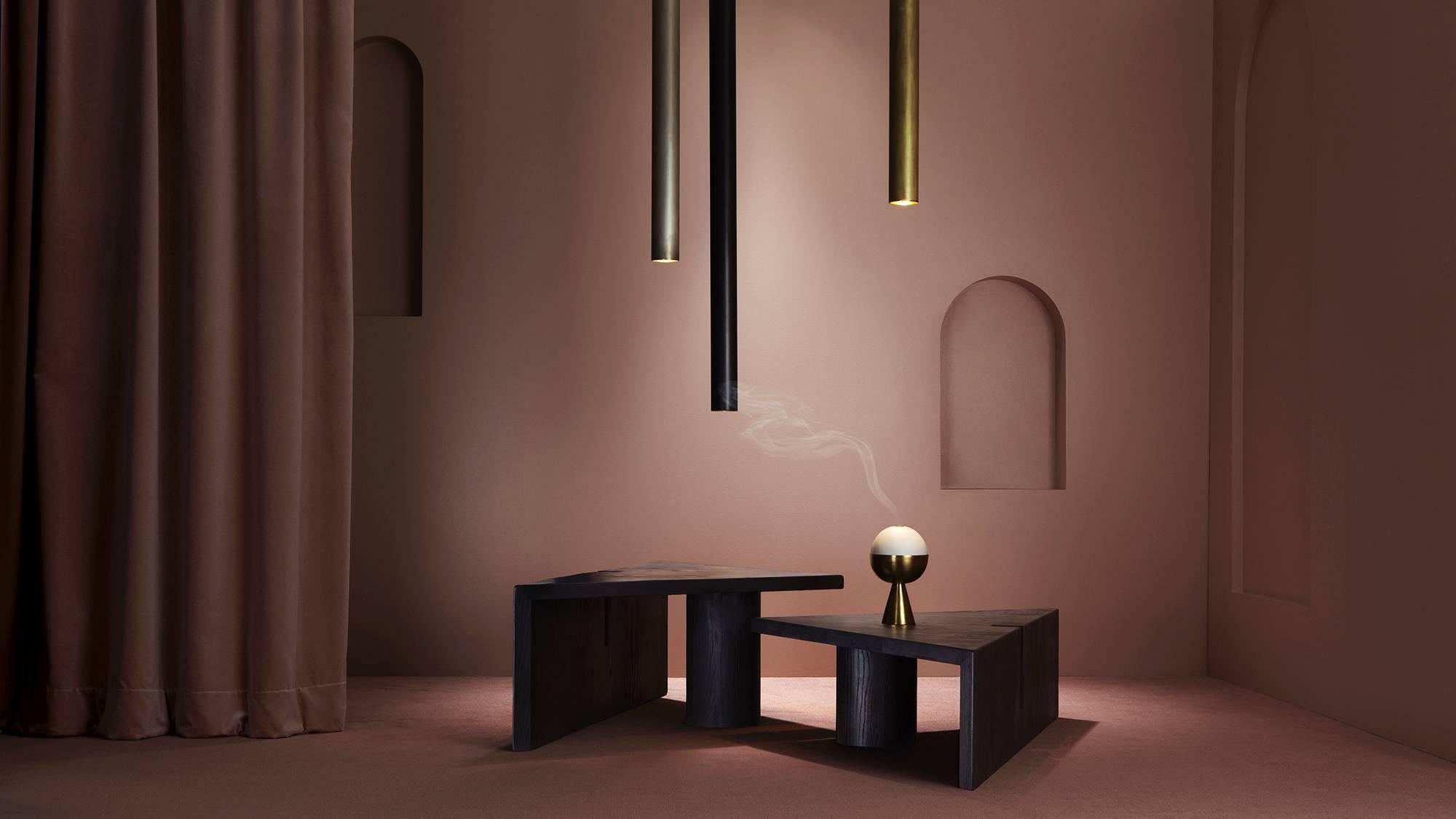 Rendered in thick sandblasted ash, portal tables conjure the proportions of ancient structures and the rough-hewn texture of primitive furniture. Notched reveals in the robust material establish points of entry, emphasizing the tension between mass