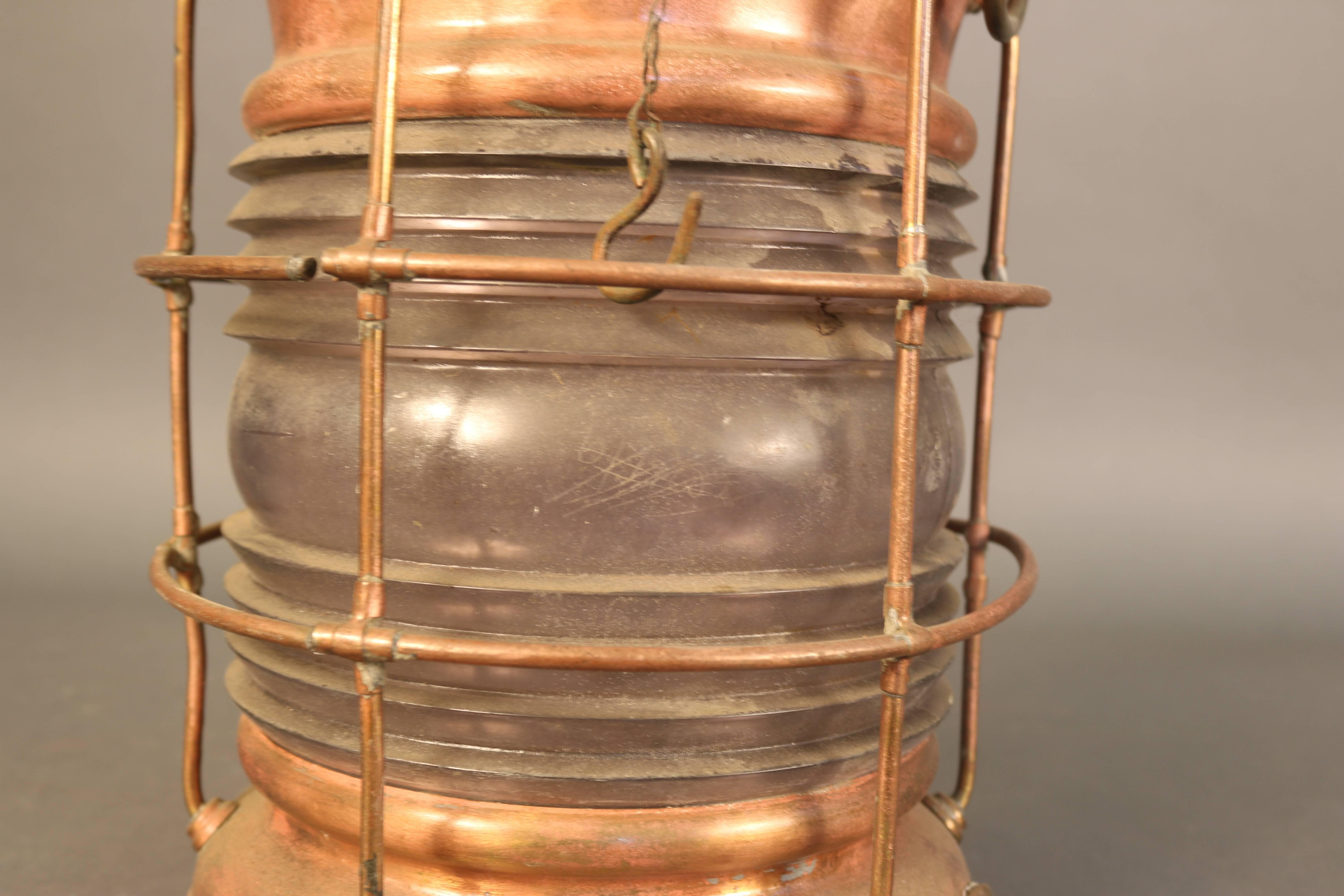 Solid copper anchor lantern with Fresnel glass lens, protective cage and hinged and vented top. 