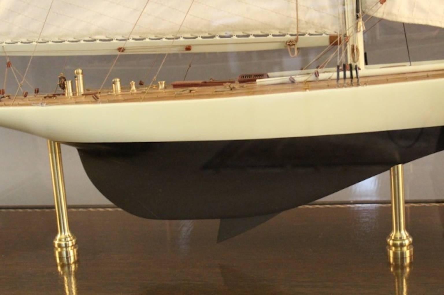 Highly detailed model of the 1930 America’s Cup yacht “Enterprise." Brass deck fittings include binnacles, cleats, winch, capstan, helm stand with carved wheel, skylights, hatches, and rope coils. Rigged with a full suit of sails and displayed