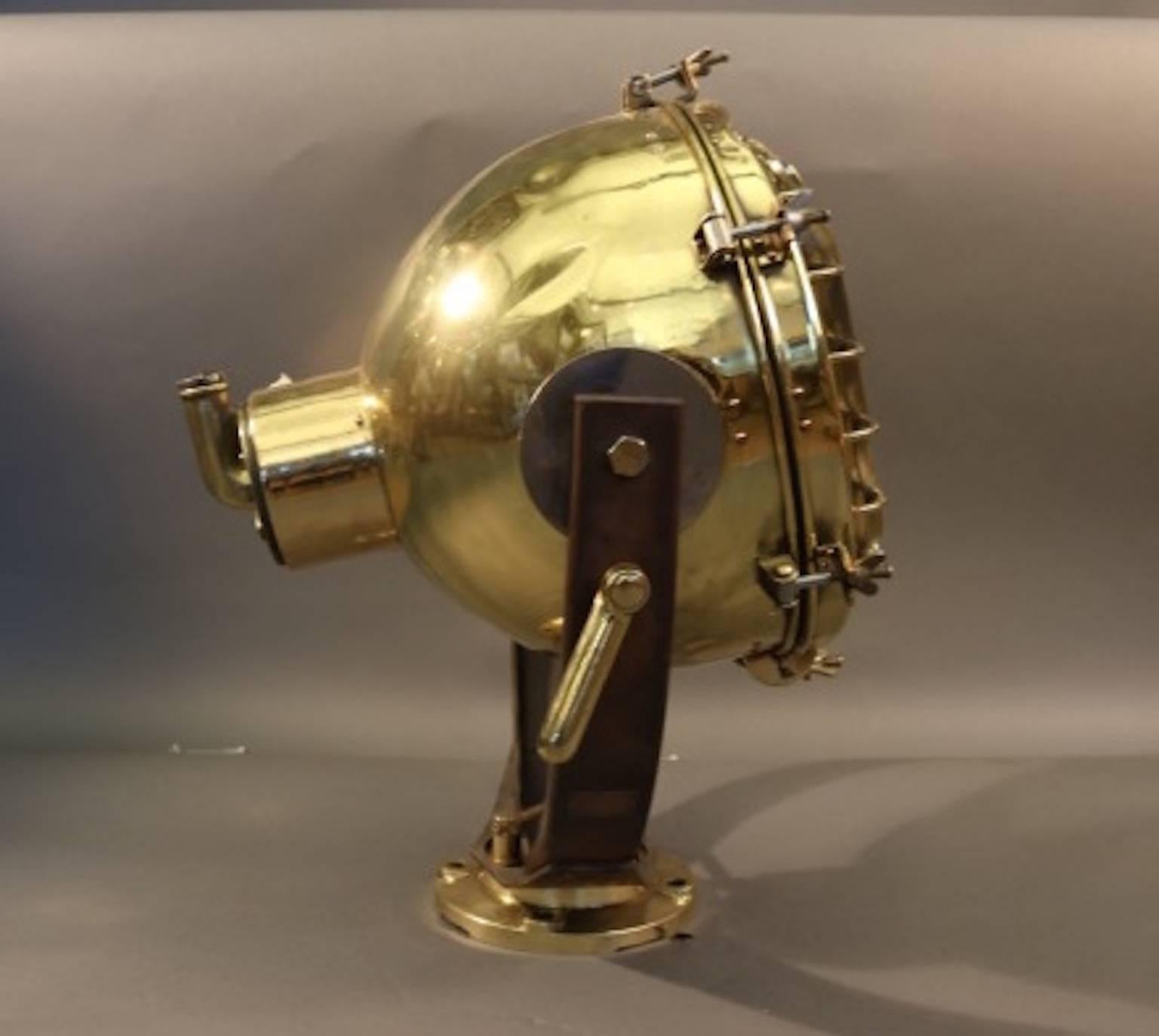 Substantial brass ship's cargo light with glass lens, protective cage, pedestal base, and etc.