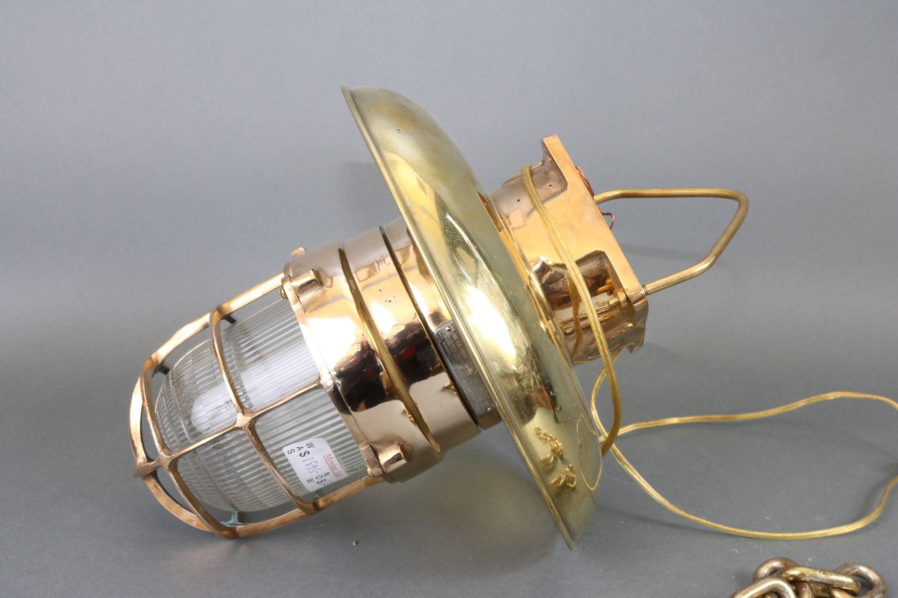 Solid brass ship's light with hood. Heavy hanging fixture with hanging chain, spun brass hood, fresnel lens, protective brass cage. Measures: 13 x 14.