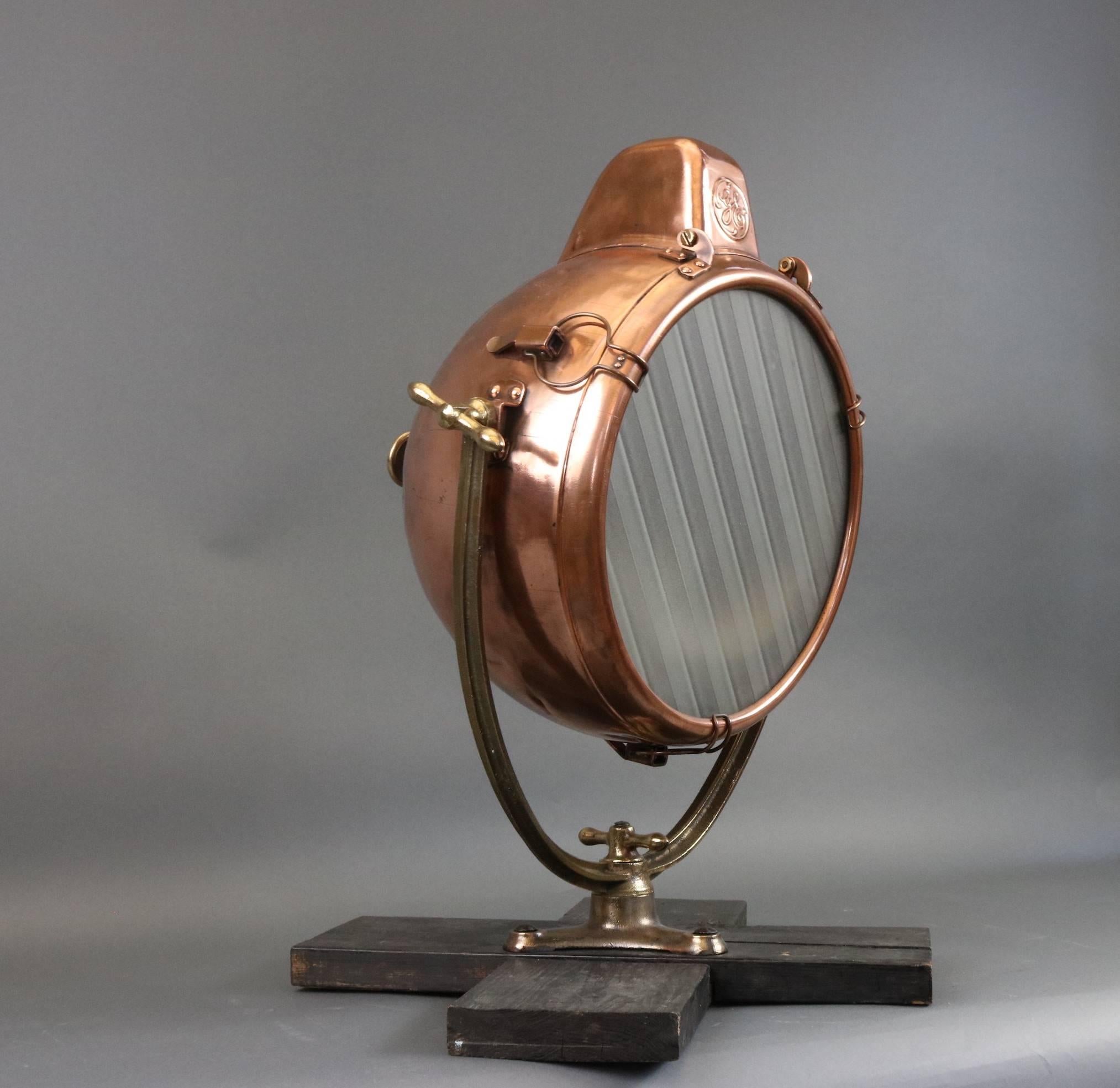 Polished copper beacon with frosted glass lens. Mounted on an iron yoke with wood base. Measures: 24" long x 20" wide x 31" tall.