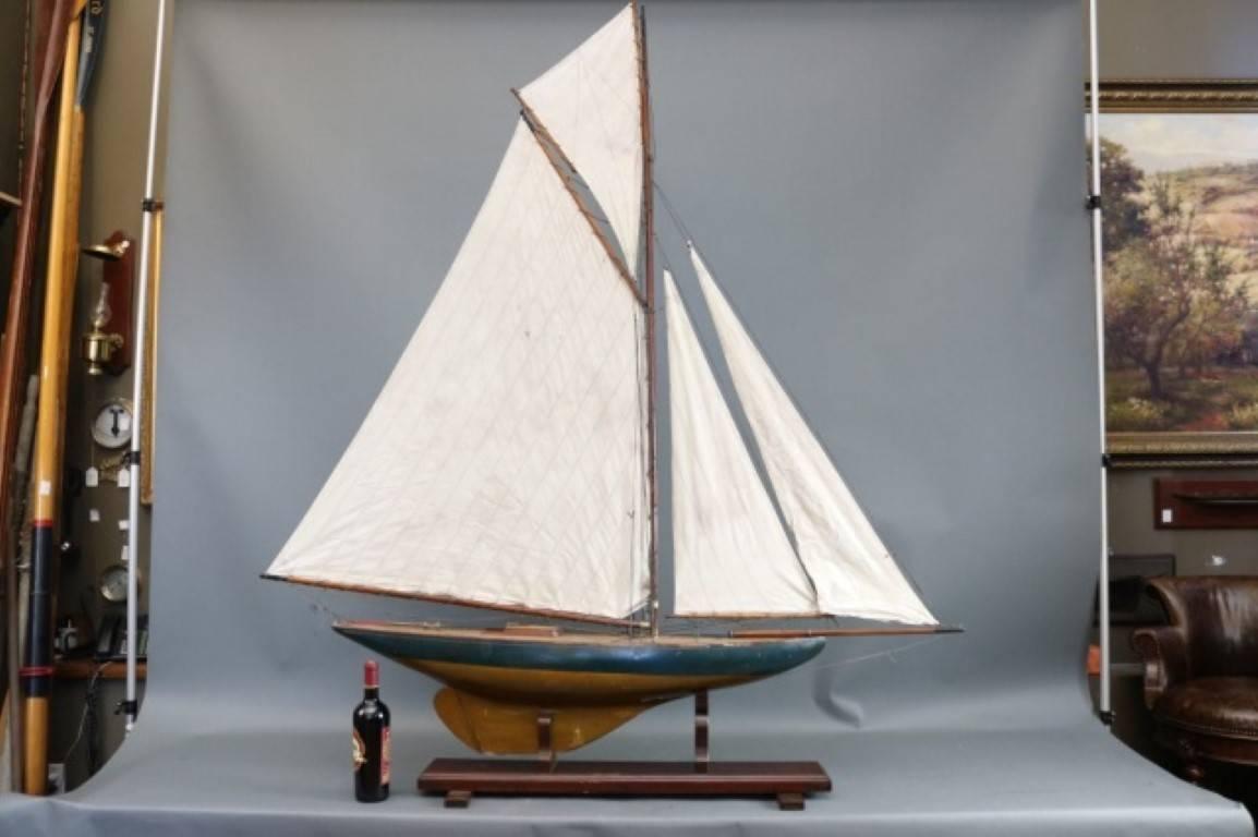 Vintage gaff rigged American pond yacht model. Rigged with a full suit of sails including mainsail, two gaffs and a flying club. Brass fittings, varnished deck. Dimensions: 64" L x 8" W x 74" H.
