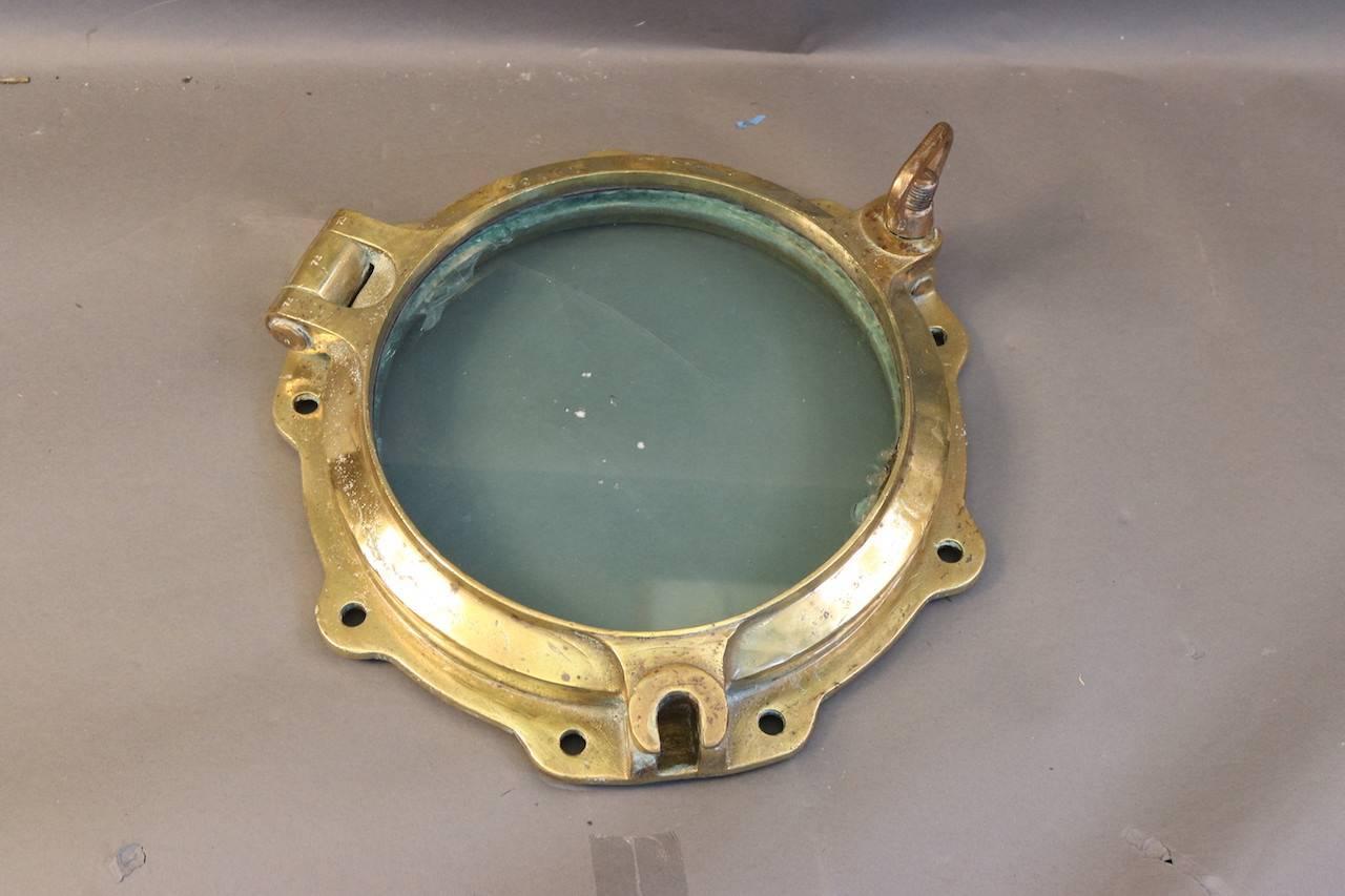 Large authentic brass ship's porthole with one bolt and a scalloped edge. Glass has imperfections.

Overall dimensions: 16" x 11 1/2" glass.