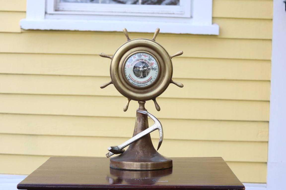 Aneroid barometer with ship's wheel bezel on pedestal and anchor detail. Reads "Clear" on a clear day by Watrous.

Dimensions: 13.5" height x 8.5" at its widest. 

         