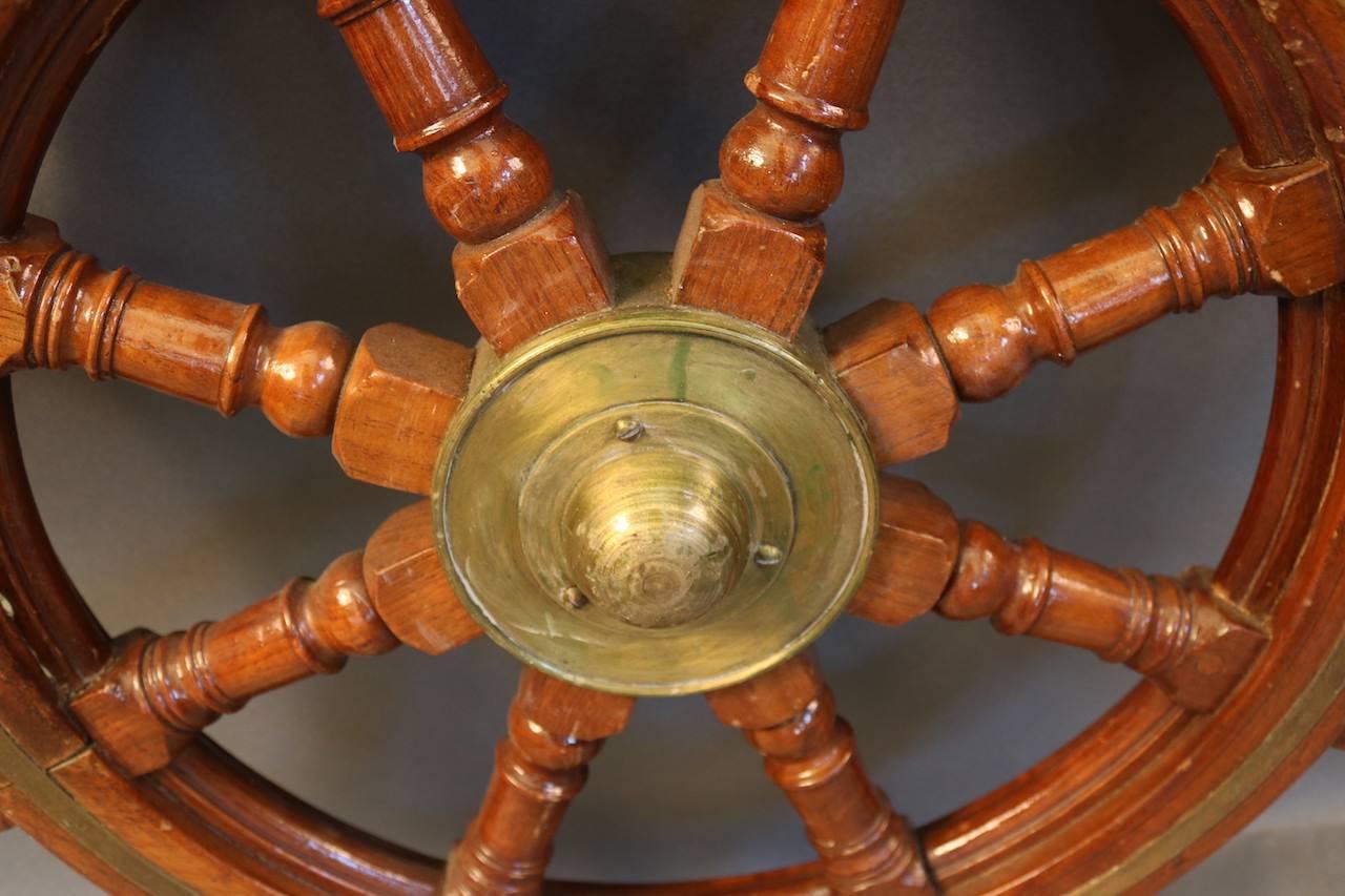 Antique ship's wheel with a turned brass hub and band inlay. Some signs of distress.

Overall dimensions: 32" diameter.

   