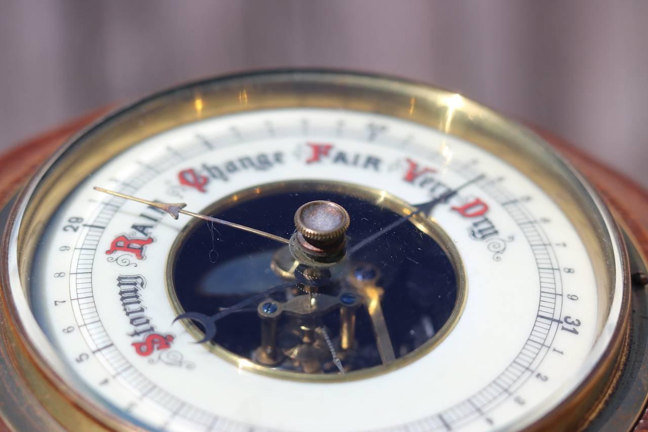 Aneroid barometer with readings: Stormy, rain, change, fair and very dry. Mounted onto a spun wooden backboard with hanging loop. 7" overall diameter x 4" face diameter.