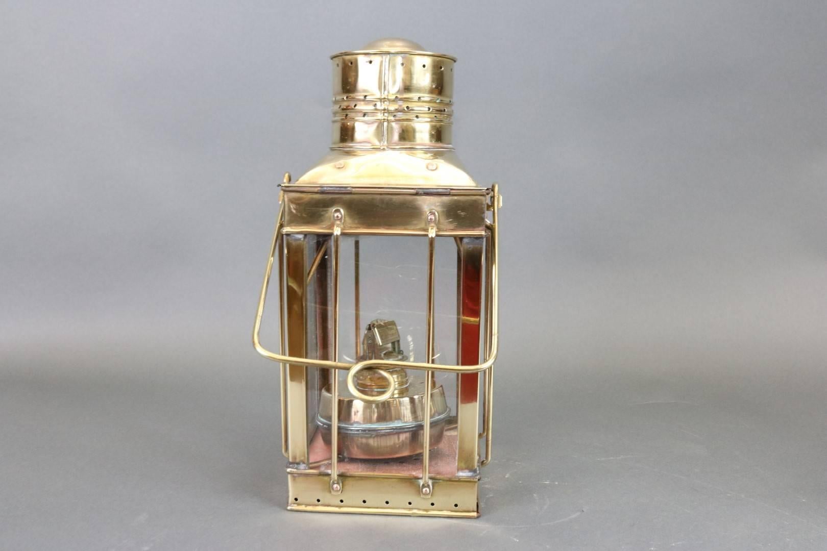 Highly polished ship's lantern by the English firm Davey. Vented top, carry handle, oil burner, and etc. Dimensions: 7" L x 7" W x 15" H.