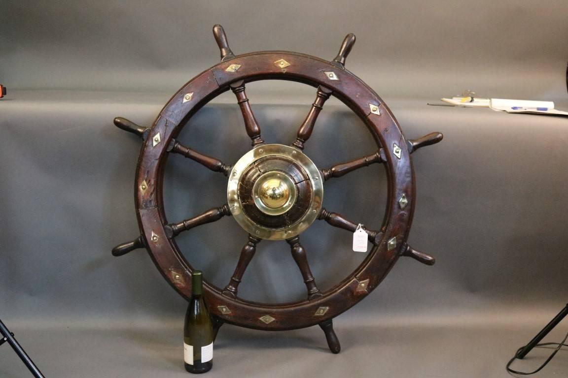 Authentic early 19th century yacht wheel with eight spokes and brass and diamond shaped inlay and a massive brass hub.

Overall dimensions: 42" diameter.