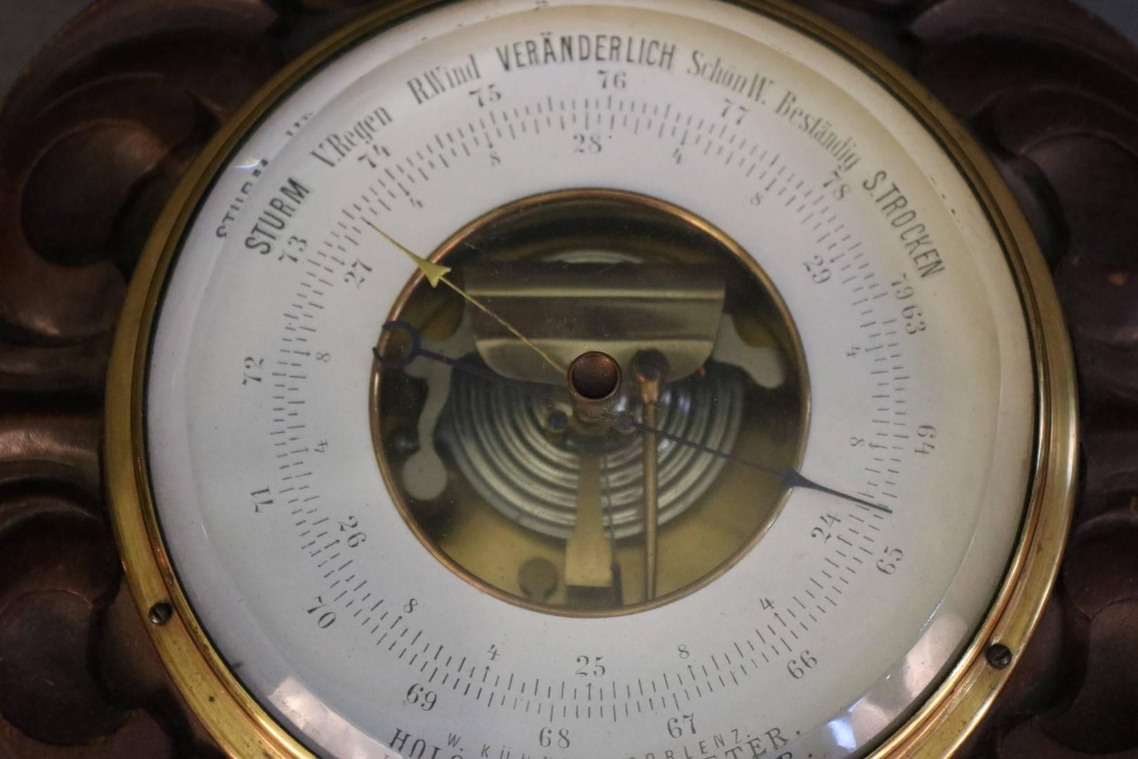 Polysteric barometer with carved wood backing. Readings in German. Manufacturered by W. Kuhanu Coblenz. Dimensions: 5" face D x 11" x 8" with base.
