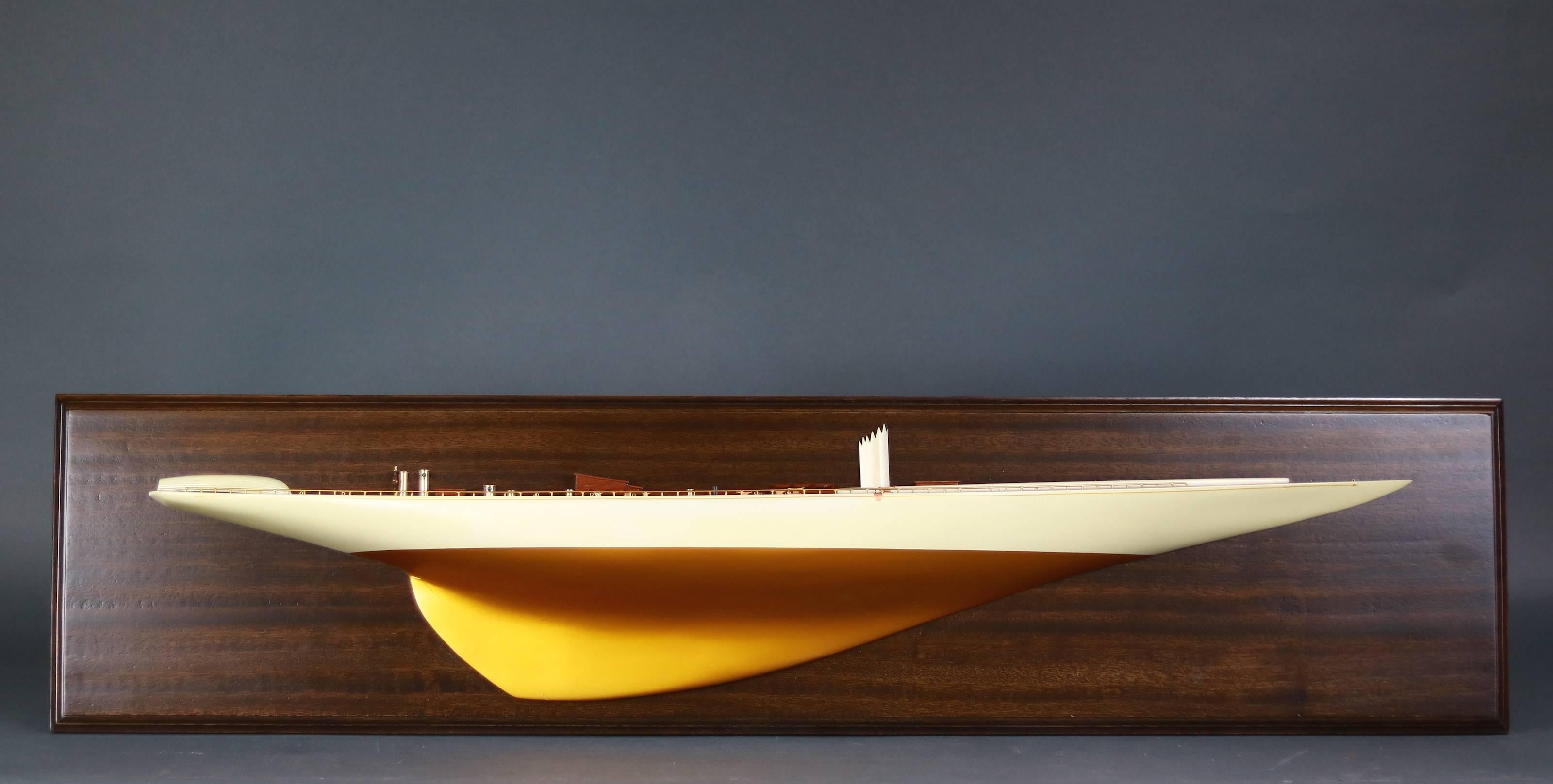 Half model mounted onto a mahogany backboard of the 1934 America's Cup yacht Rainbow.

Model is painted ivory above the waterline and metallic gold below the waterline. Very detailed.

Measure: 42 1/2