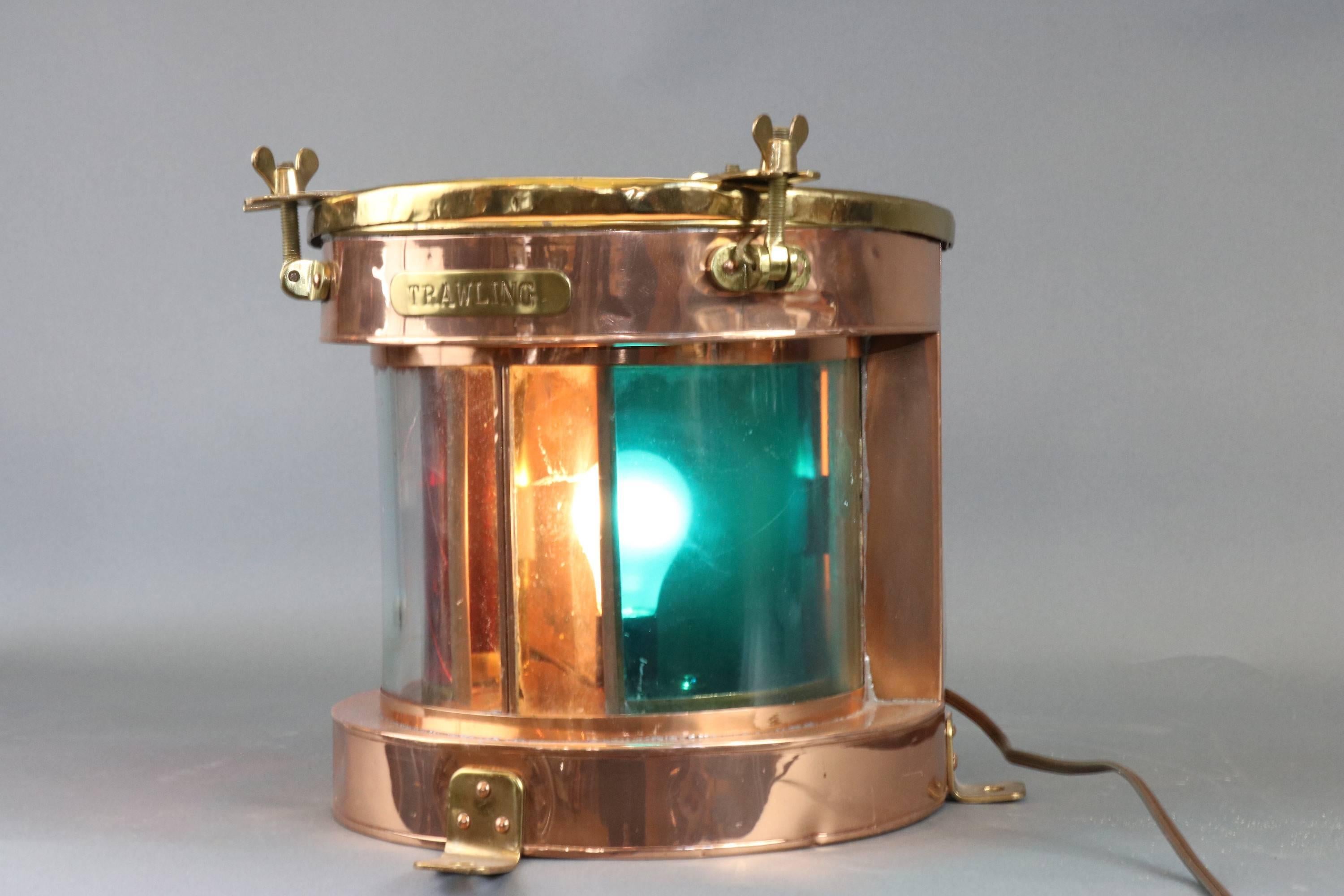 Rare copper and brass ship's trawling lantern. Copper housing with brass top, curved glass front lens with sliding internal filters of red and green. Red filter is cracked. 

12 x 12 x 10 1/2" high
