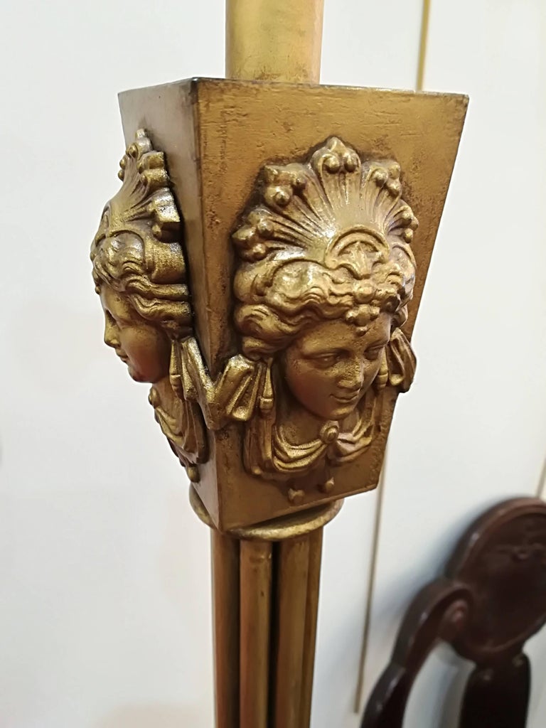 Neoclassical floor lamp with heads decor, gold patinated metal, circa 1940.