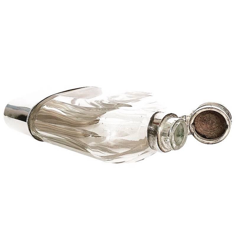 A large glass and silver plated hip flask with drinking cup.