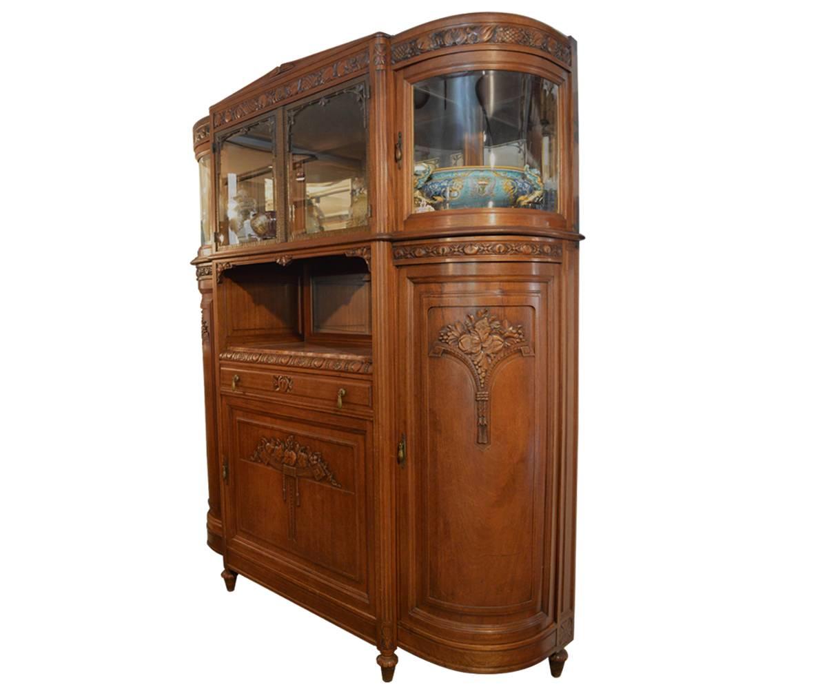 Early 20th century buffet with plenty of storage behind the three carved cabinet doors. There is a marble topped space in the center for display or serving. The glass, including the curved is all original to the piece.