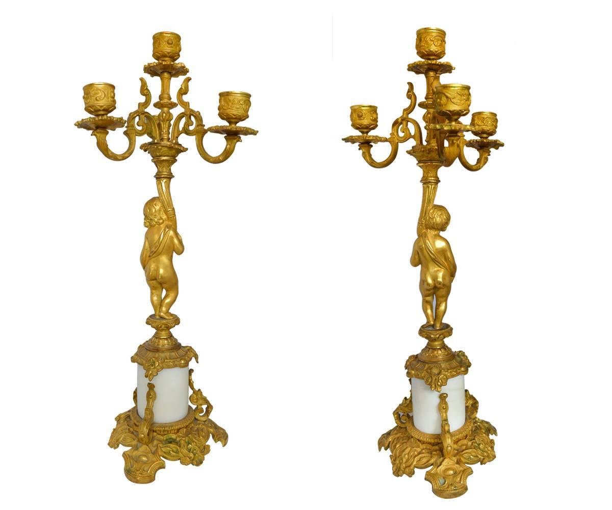 This pair of candelabra are gold gilt bronze and are intricately decorated with a white marble lower stem and gilt bronze foot.