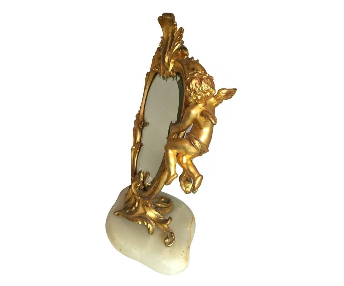 This beautiful French vanity mirror is in the Louis the XV style and has the original beveled mirror. It features a putti and is mounted on an onyx base.