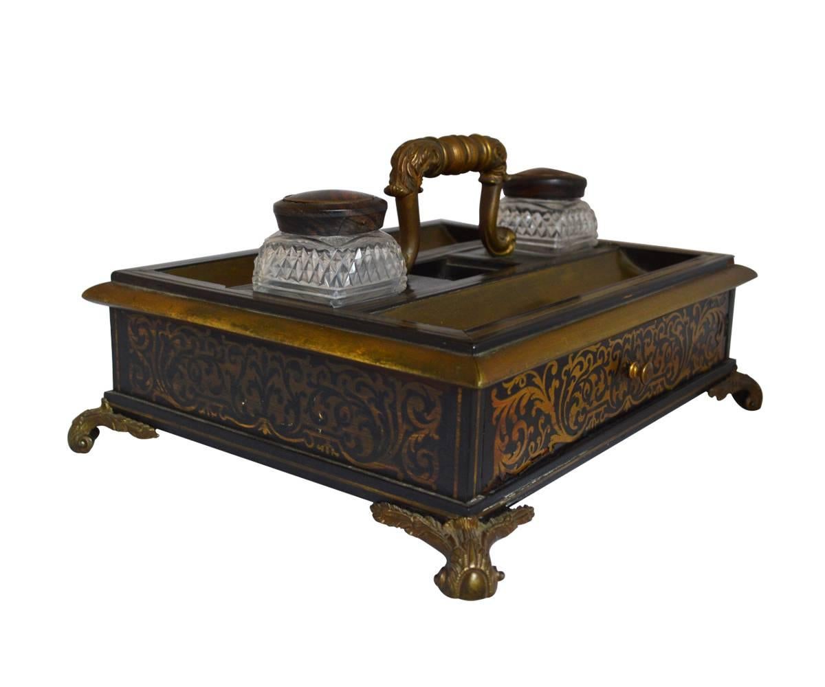 This inkwell has the Boulle style with brass inlay and features cut-glass ink vessels.