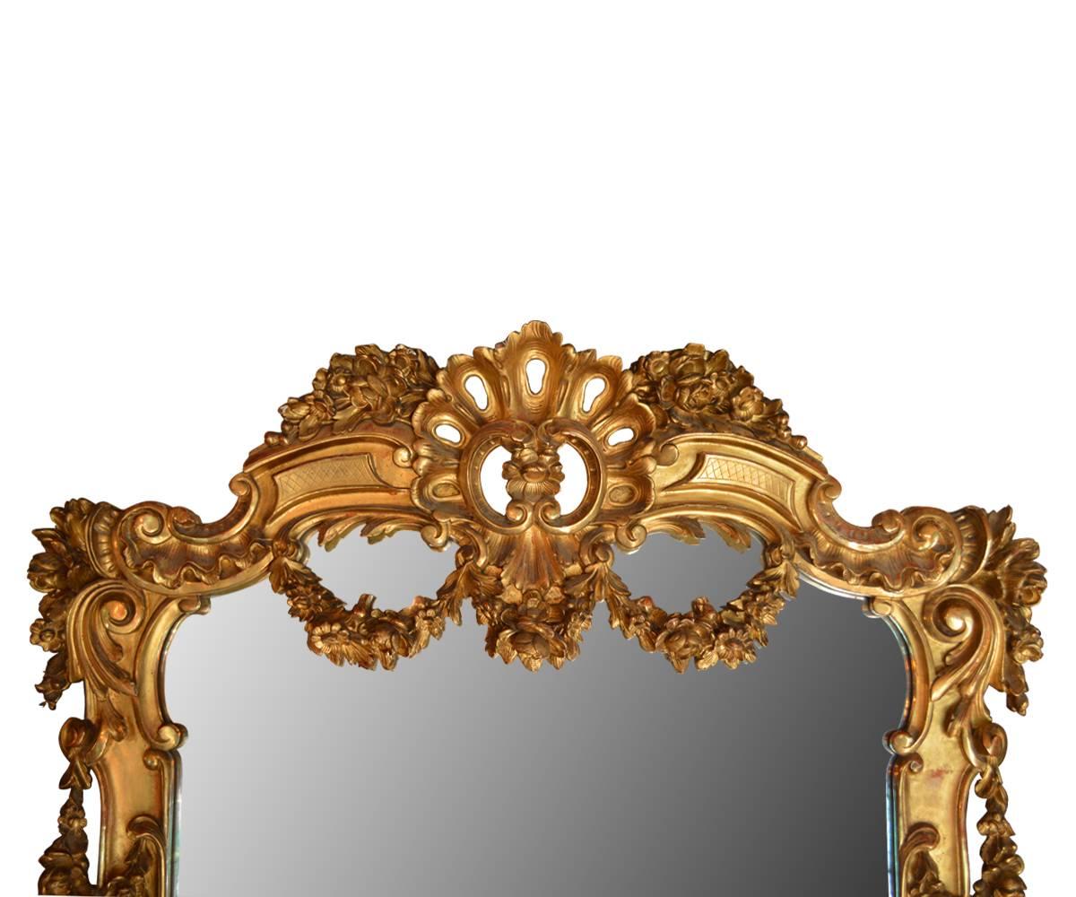 Stunning large French wall mirror with hand-carved wood and gold gilded finish frame. The high quality, deep hand-carved floral garlands design on top center and side of this frame is truly amazing. This mirror is nice addition to any modern or