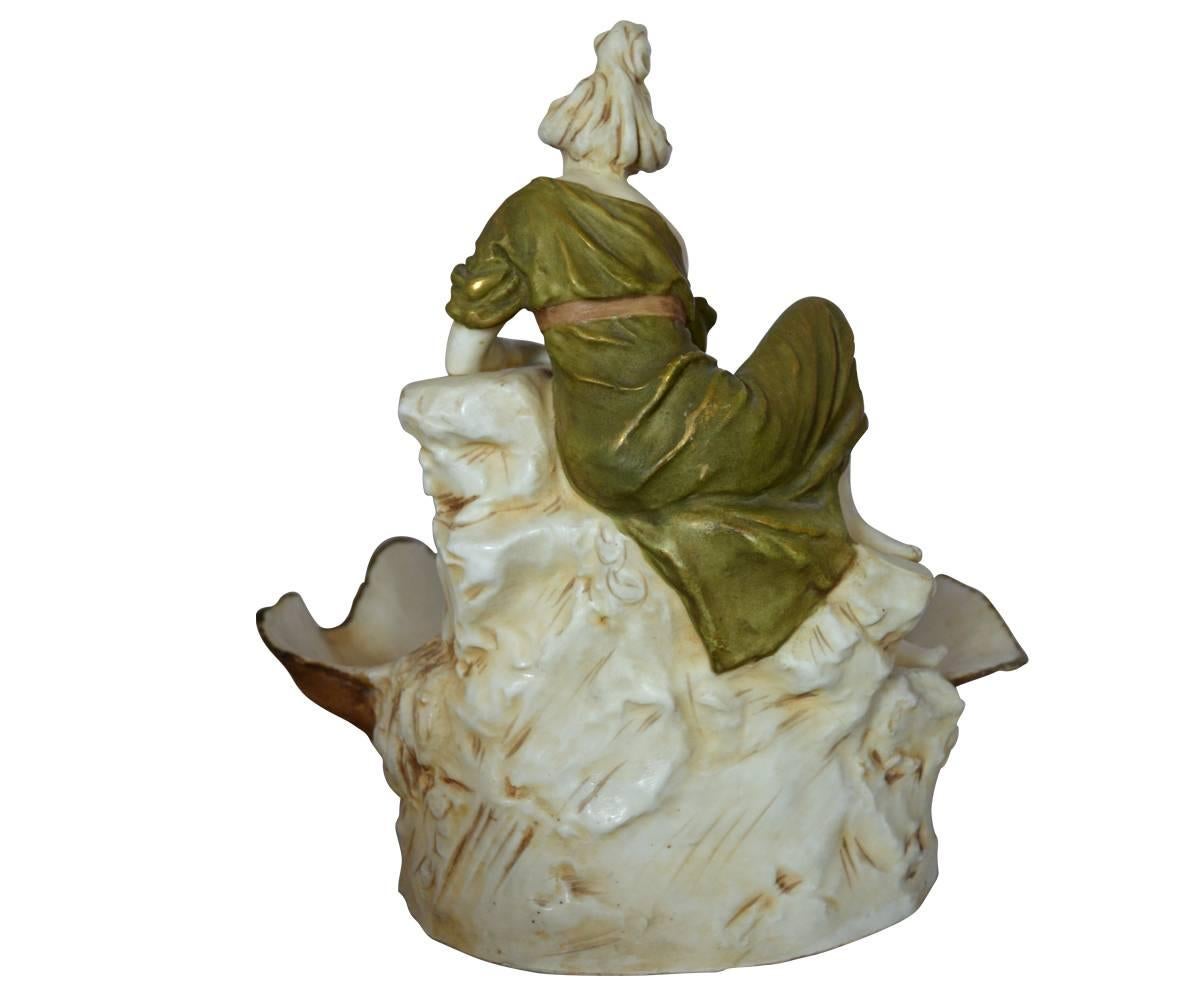 Gracefully detailed 19th century Royal Dux porcelain of woman figurine with shell and urn. Hand-painted in earth tone color of soft green and rust and beige. 
