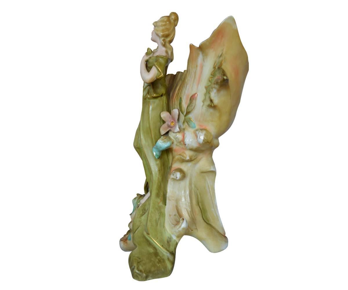 A stunning Royal Dux Bohemia porcelain figurine of Art Nouveau design featuring woman perched on large shell which is mounted on tree trunk with small roses.