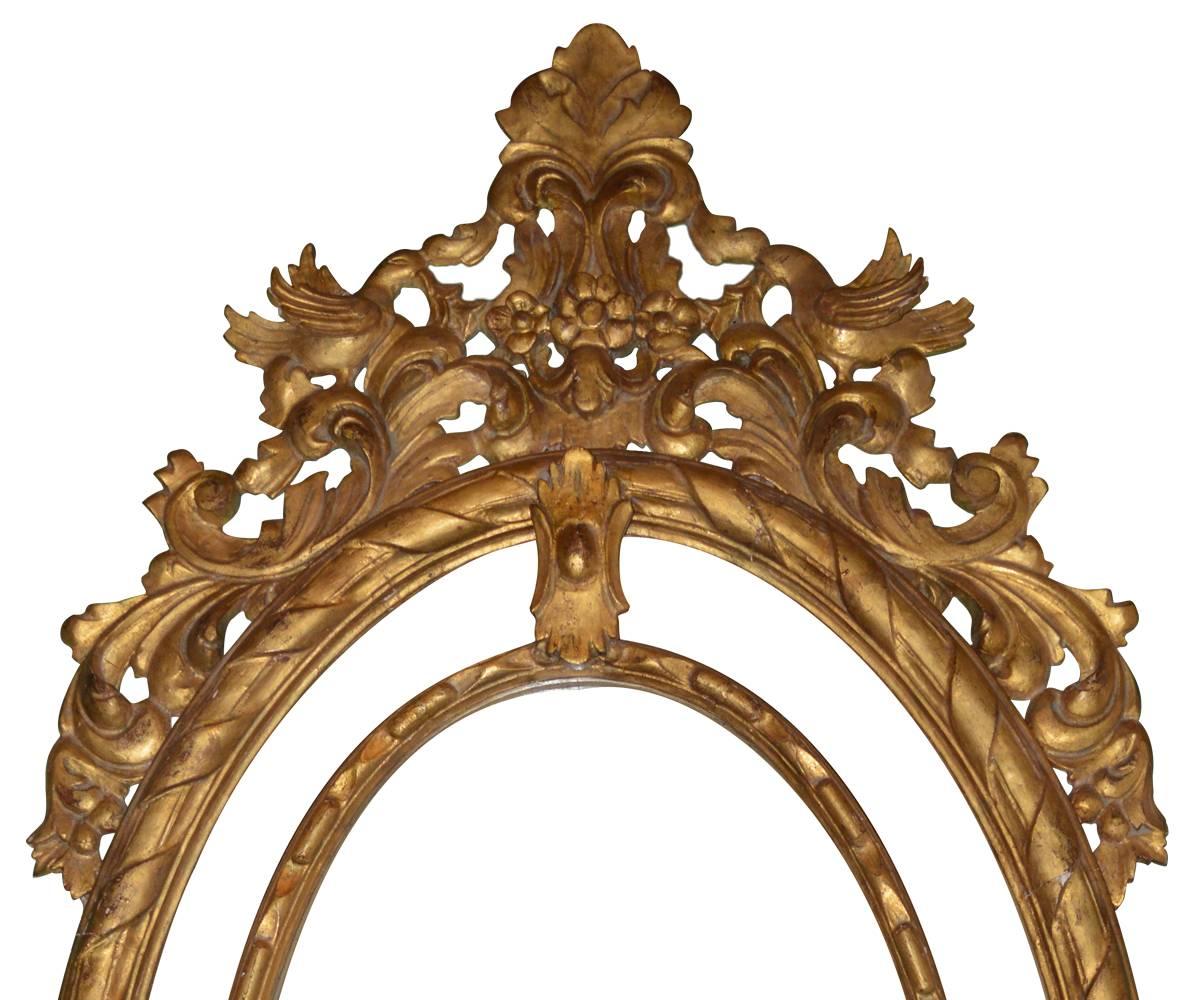Large hand-carved giltwood oval mirror in style of Hepplewhite. The well carved giltwood has openwork some of which covers the mirror giving it the appearance of multiple mirrors.