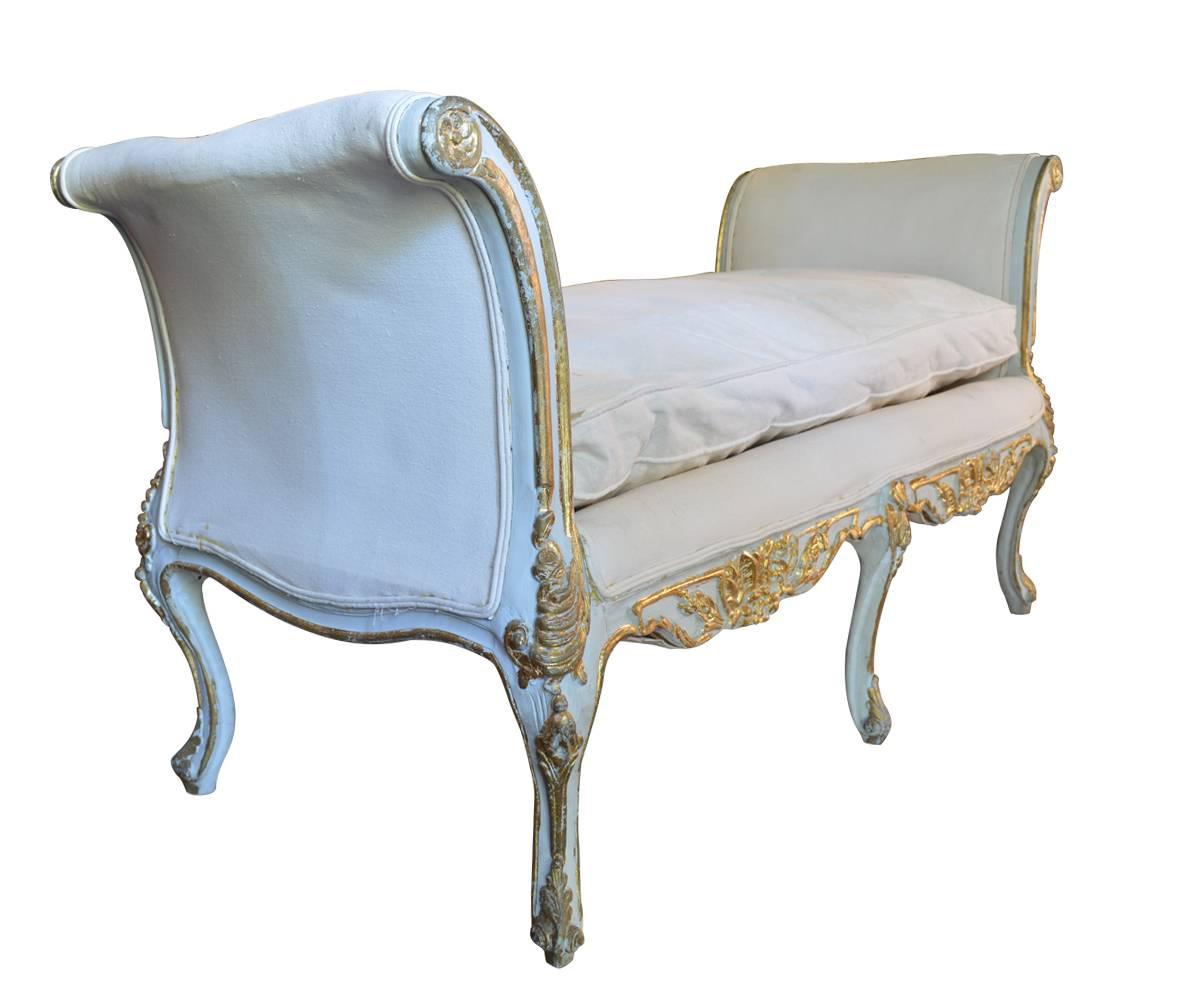 We proudly offer this 19th century gold gilded and painted soft blue color Louise XV style bench with one loose cushion and carved arms. This bench has been reupholstered in white linen fabric couple of years ago.
