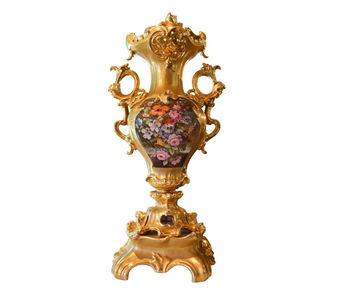 We proudly offer this gorgeous, old Paris hand-painted and gold gilded on porcelain vase. It features painted lovers on one side and painted flowers on the opposite side. It has two gilt handles two handles and matching pedestal.